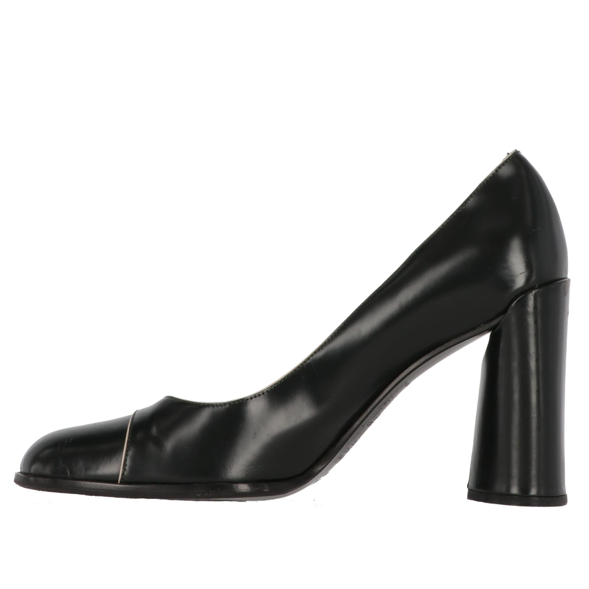 Classy and minimal shoes in the style of Prada, these black leather pumps with white contrasting thin hems. Round thick heel, cap toe stitching and round toe. 
Item shows signs of wear on the leather, heel and the sole, as shown in the