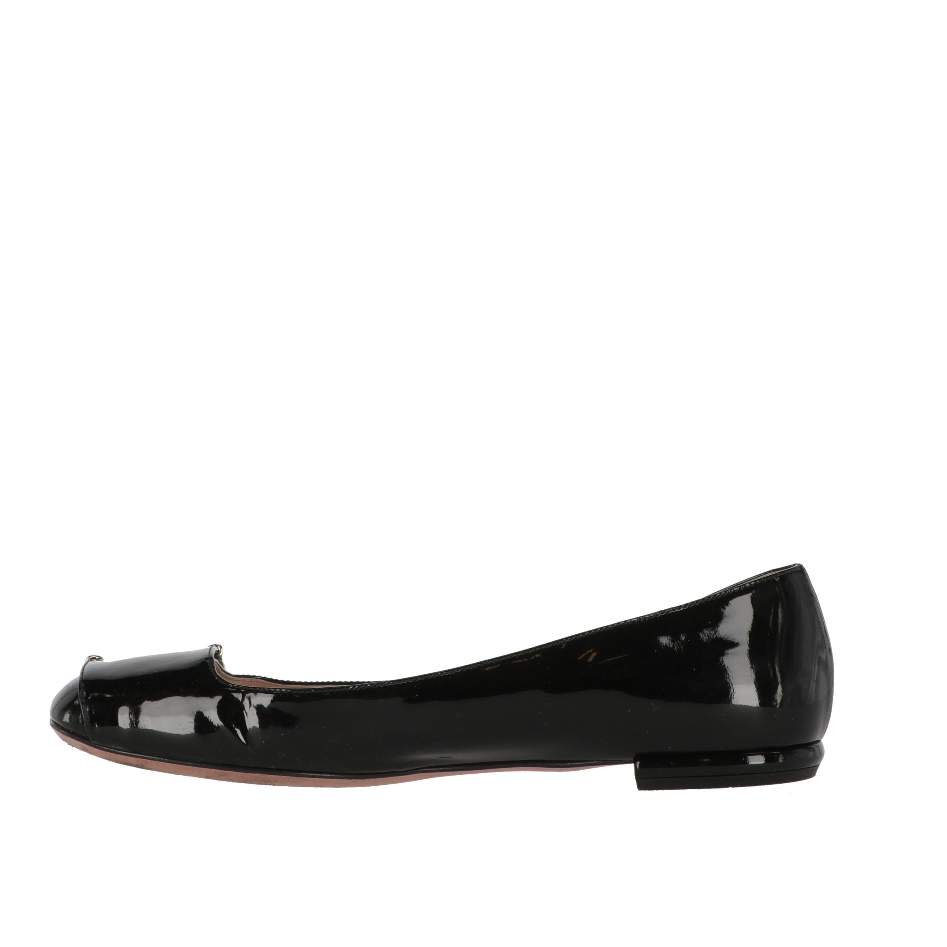 Perfect to add a touch of elegance to your everyday outfits, these Prada black patent leather ballet flats feature a round toe and fake strap with logoed silver-tone metal detail. 

They show light signs of wear and wrinkles on the leather, as shown