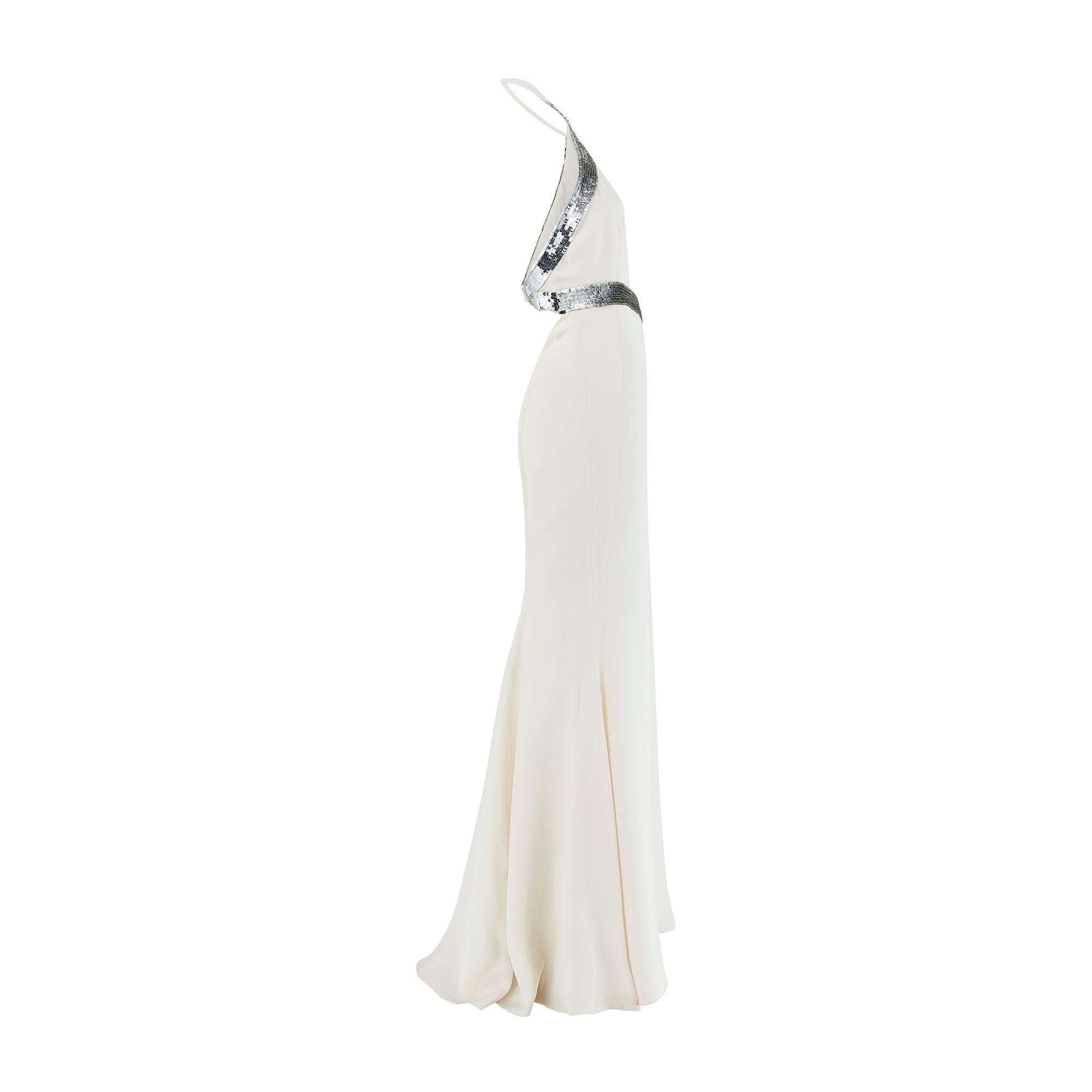 Made in Italy, this flamboyant Roberto Cavalli evening gown, circa 2010, has a curve-accentuating silhouette and high-octane embellishment. Cut from smooth white silk, it has a high halter neckline and fluid, body-skimming tailoring. This dress is