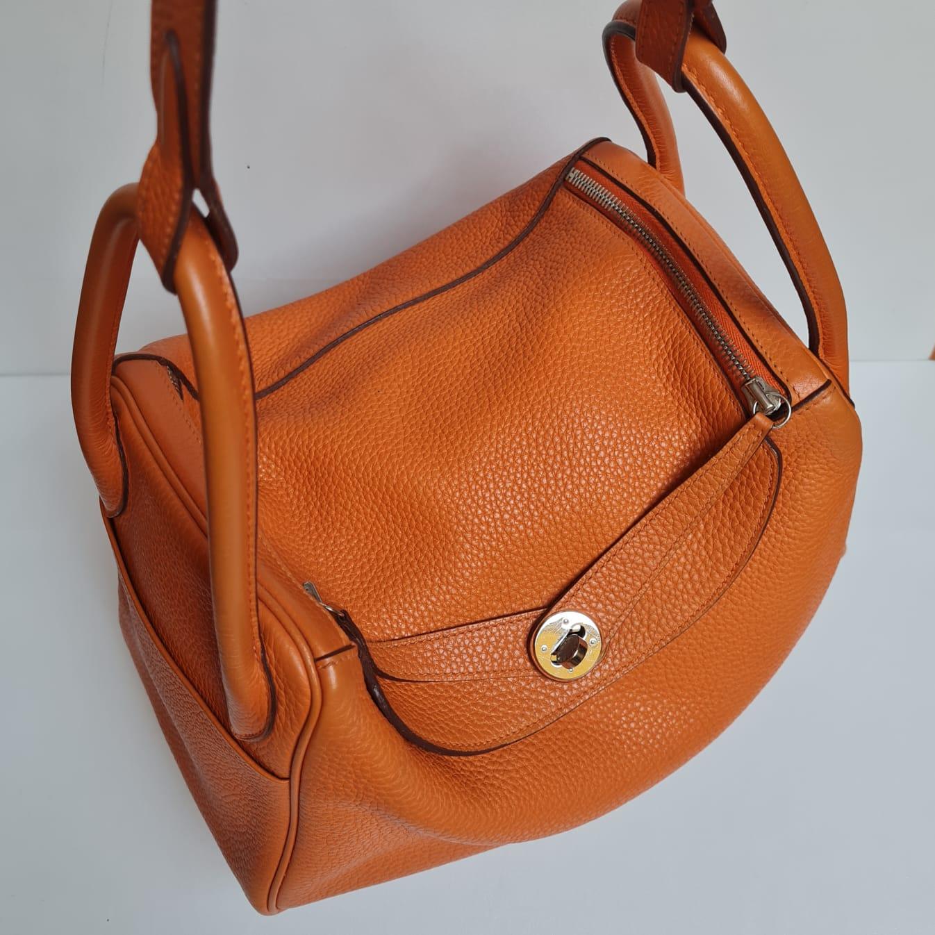 Lindy 30 in orange clemence leather and palladium hardware. Overall still in good condition, with slight rubbing on the corners of the bag and handles as seen on pictures. Light tarnishing on the hardware. Stamp Square O (2011). Comes with its dust