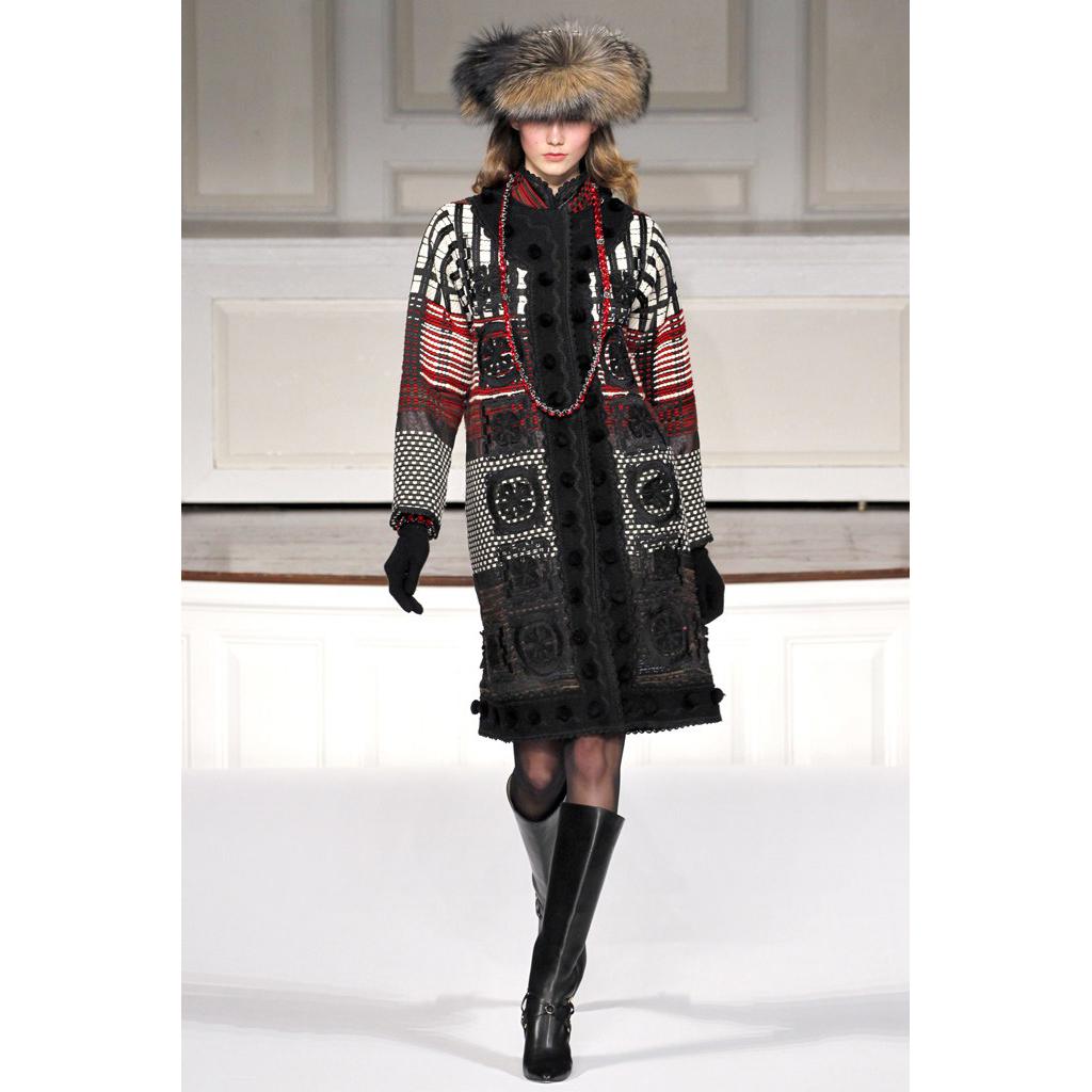 This is a wonderful Oscar de la Renta coat in black white and red with wool pom poms. This incredible tweed coat has side slit pockets, wool boucle trim, an interesting mixed pattern and soutache trim. We love this particular piece and estimate it