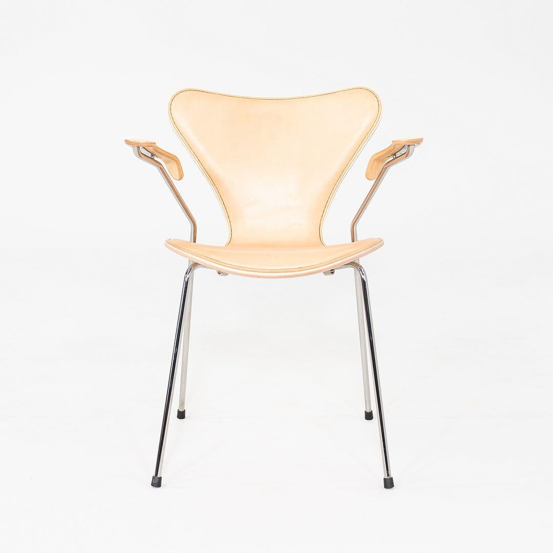 This is a Series 7 Dining Arm Chair, originally designed by Arne Jacobsen in 1955. This particular example was produced by Fritz Hansen in Denmark and dates to the year 2012. The chair features a molded maple veneer shell with natural leather