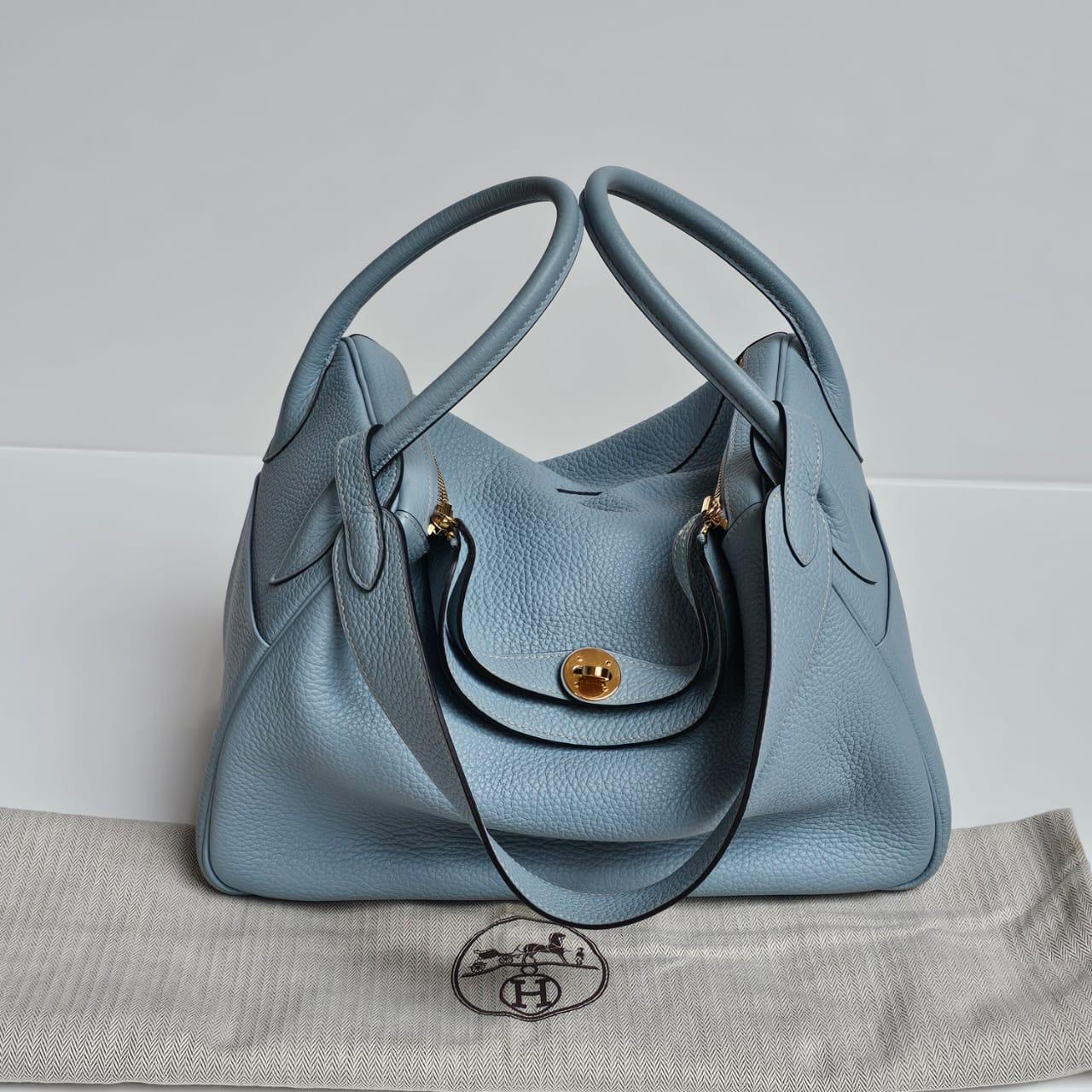 Classica Lindy 34 in ciel clemence blu con finiture dorate. Un blu pastello molto chiaro che si sposa molto bene con la ferramenta dorata. Piazza del francobollo P (2012). Lievi sfregamenti sugli angoli. Viene fornito con la sua borsa per la polvere.