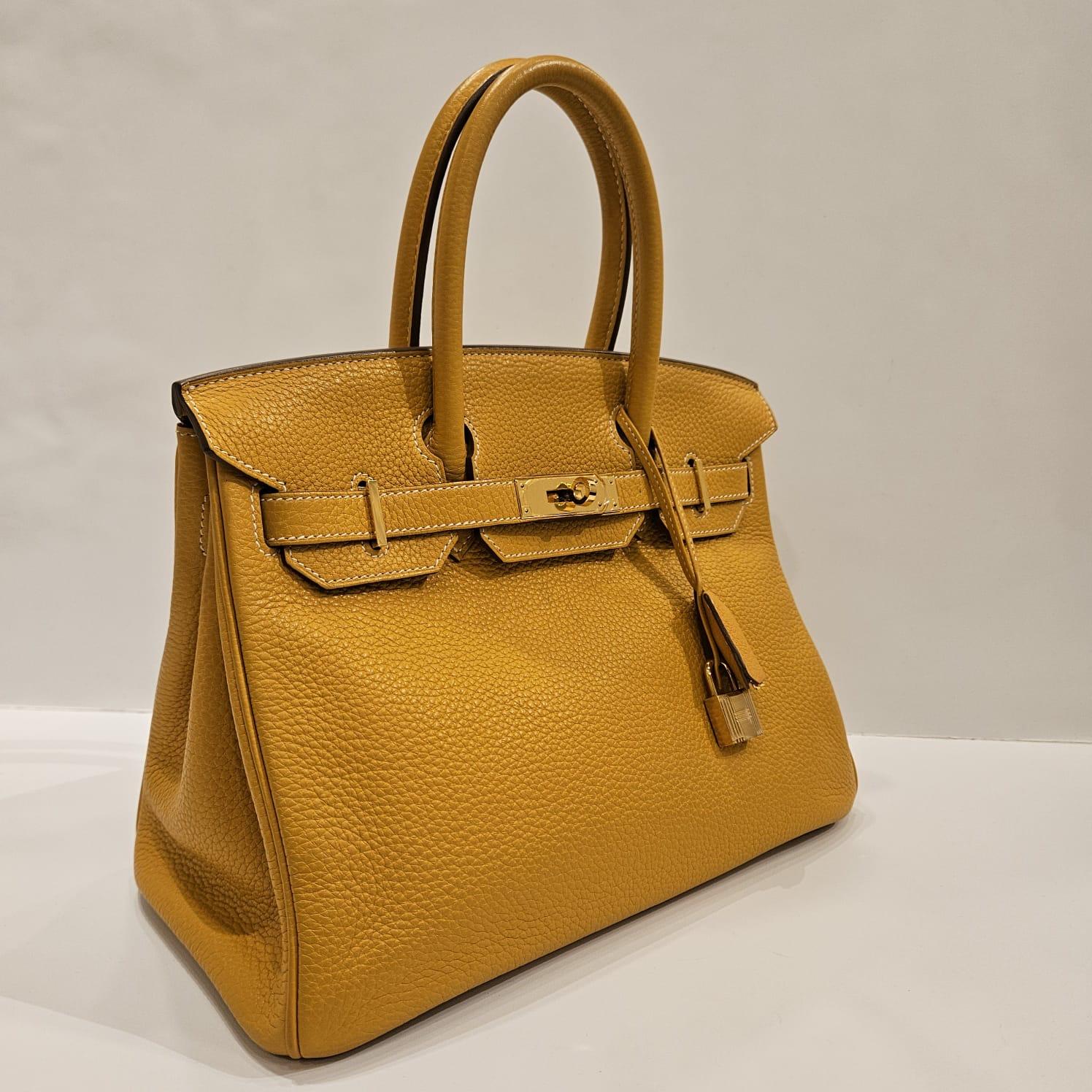 Birkin 30 in moutard clemence with gold hardware. Slight used to the bag with minor tarnishing on the hardware and rubbing on the corners. Turn-lock is still stiff. Slight rubbing to the handles (lost its texture). Comes with its copy receipt from