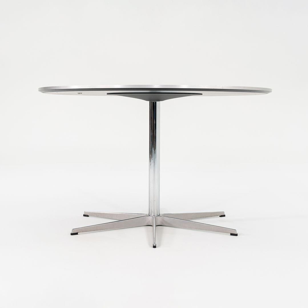 This is an A825 Model Circular dining table. Originally designed by Piet Hein and Arne Jacobsen in 1968. This particular example was produced by Fritz Hansen in Denmark circa 2012. The table features a black laminate tabletop atop an aluminum base.