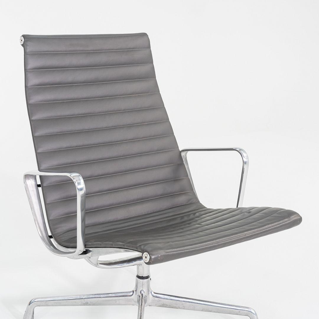 These are Eames Aluminum Group Lounge Chairs, model EA316, originally designed by Charles and Ray Eames for Herman Miller in 1958. These particular examples date to 2013. They are upholstered in grey leather, 2111 Graphite color from Austria, and
