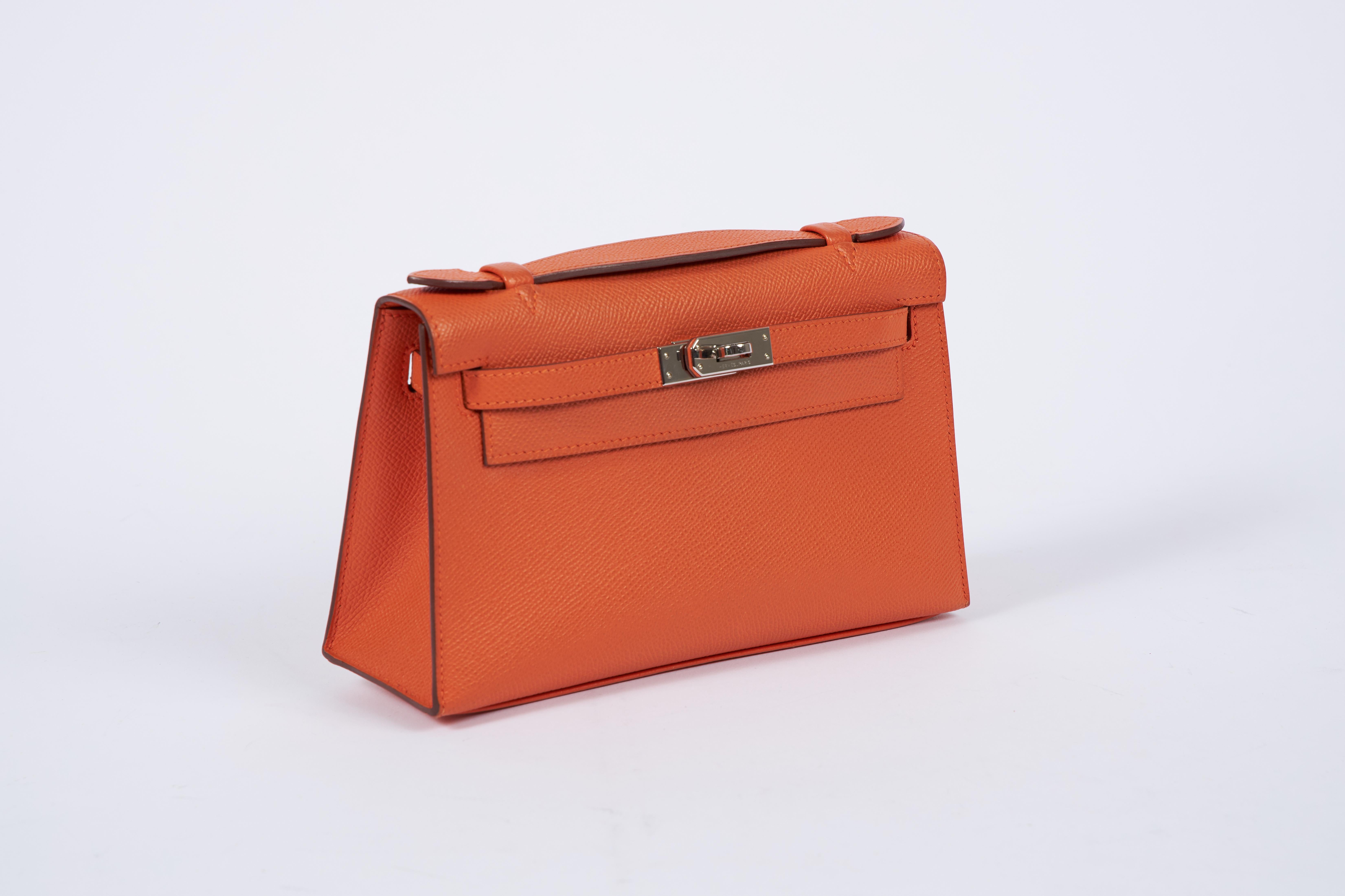 Hermes orange epsom leather Kelly pouchette with palladium hardware. Partial plastic on hardware. Date stamp Q, 2013. Comes with original dust cover.
