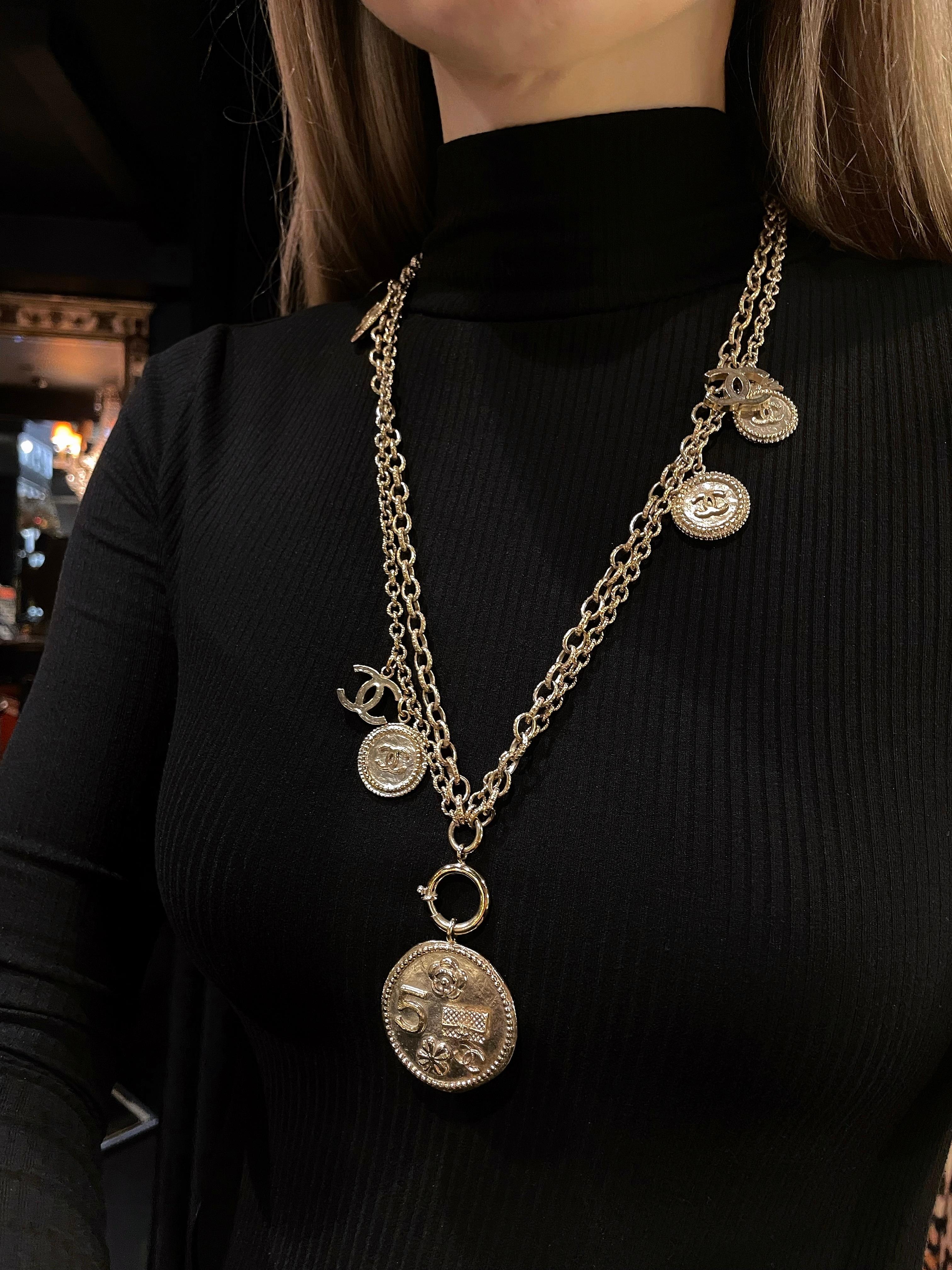 Diese elegante Halskette aus doppelten Kettengliedern wurde von Chanel im Jahr 2014 für die Frühjahrskollektion entworfen. Es enthält Münzen und Charme, die sich umdrehen lassen und verschiedene kultige Chanel-Motive zeigen. 

Farbe:
