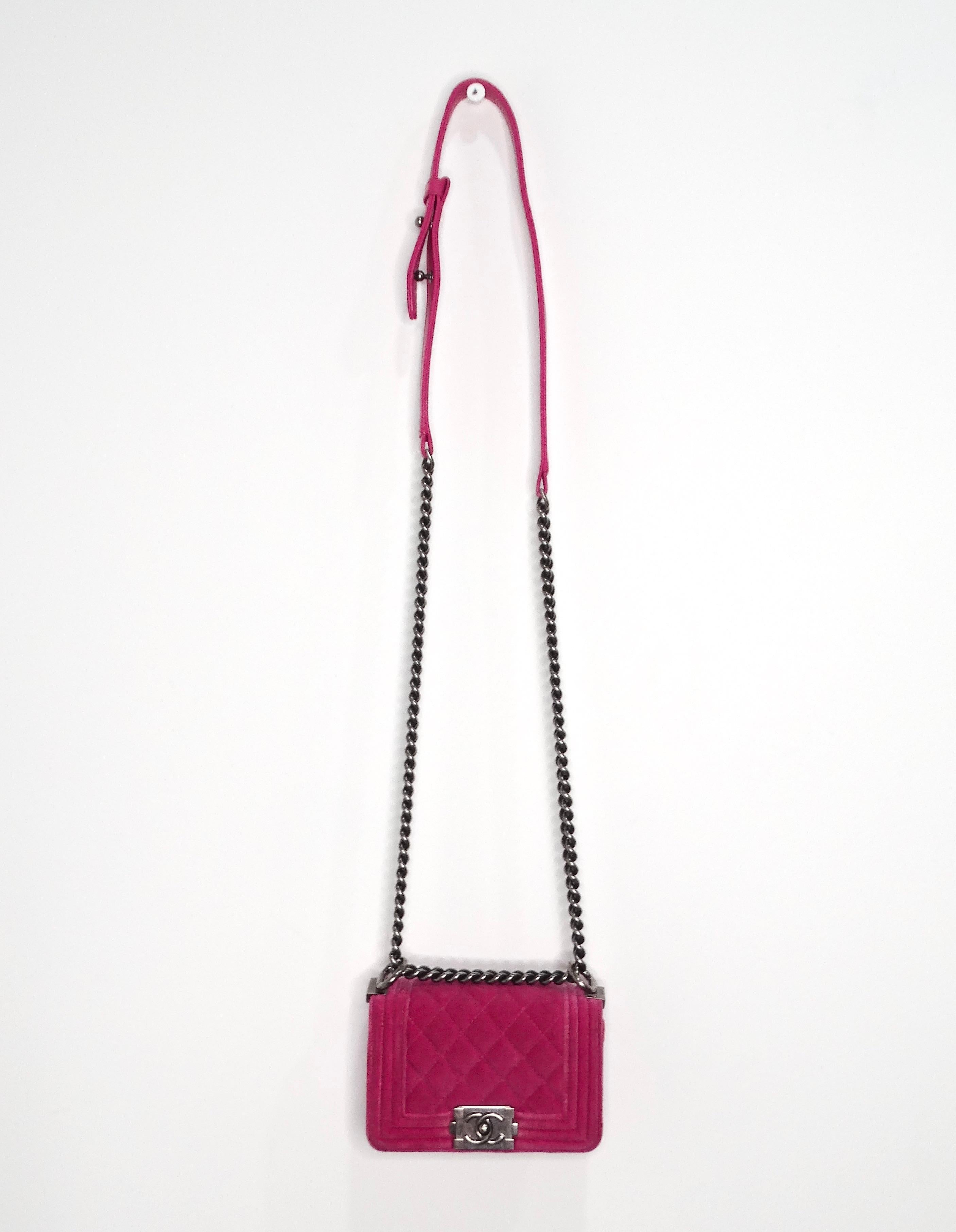 The 2014 Chanel Fuchsia Mini Velvet Boy Bag with Ruthenium Hardware is a striking accessory that embodies both elegance and sophistication. This bag features the iconic quilted design that the Boy Bag line is renowned for, with a boxy shape that