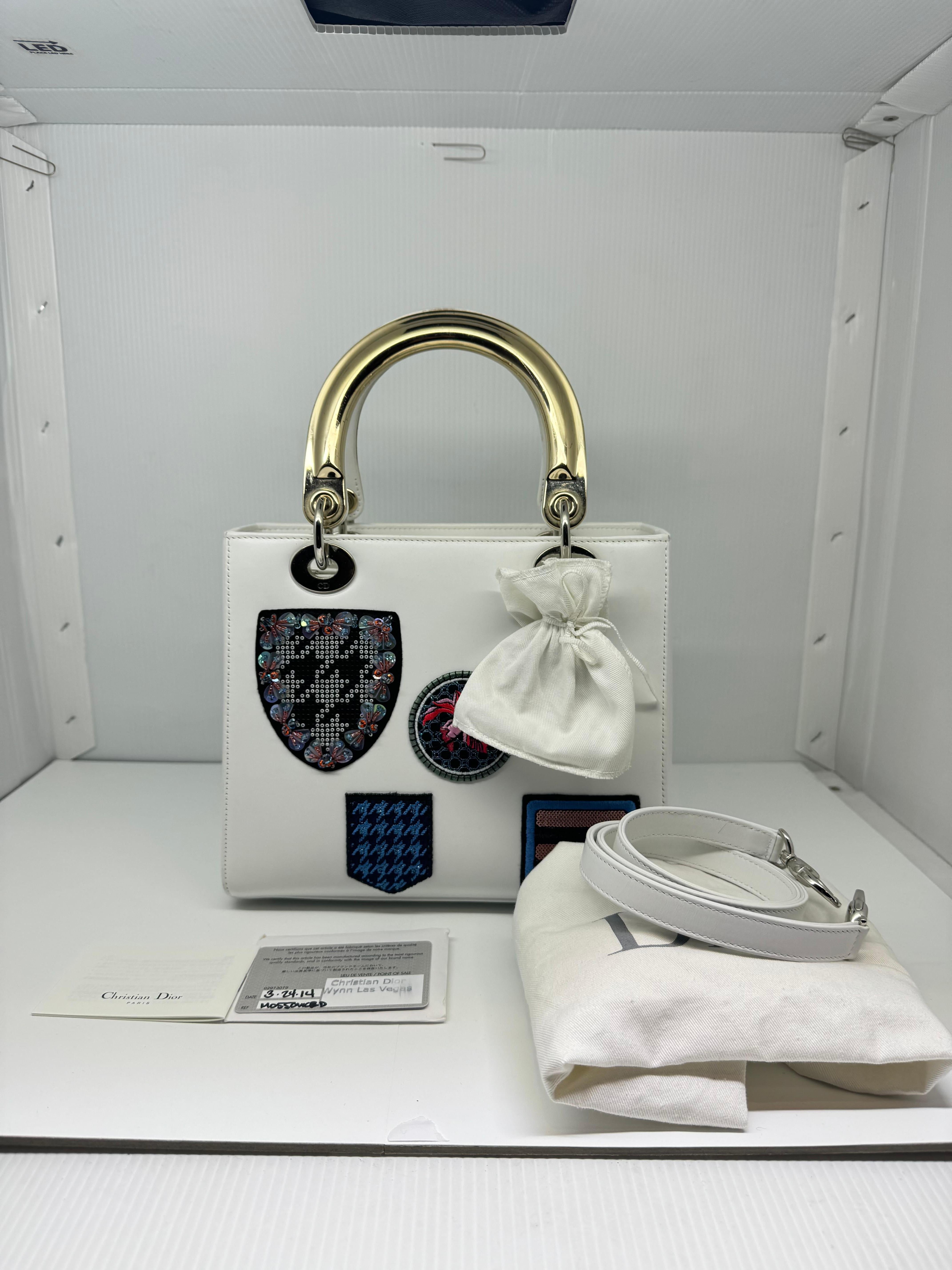 Limited edition 2014 medium lady dior bag in white leather with patches. Faint rubbing on the corners and zipper trims. Metal handles shows slight scratches. Patches are still in pristine condition. Comes with its card, booklet, dust bag and strap.