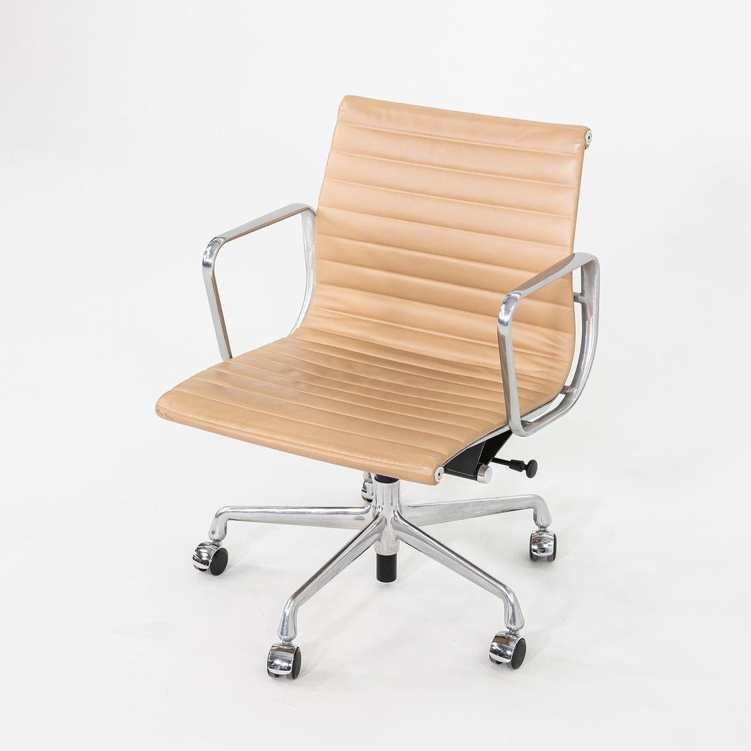 These are Eames Aluminum Group Management Desk Chairs, Model EA335, designed by Ray and Charles Eames for Herman Miller in 1958. These particular examples were produced in 2014. The design features a cast aluminum frame with a pneumatic adjustable