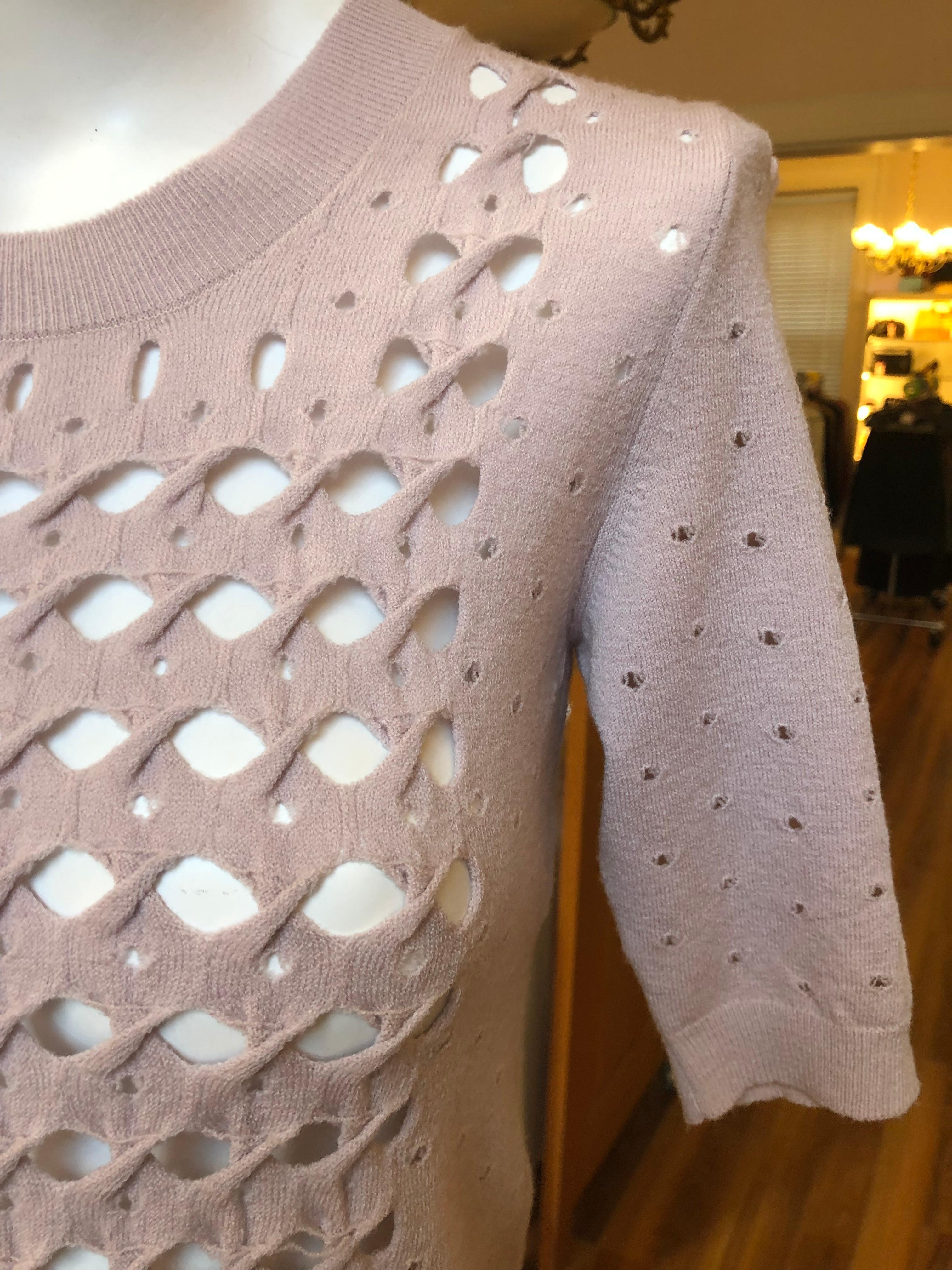 Lovely delicate lace knit 87% wool and 13% polyester sweater in a pale lilac color. The elbow length sleeves have a braided pattern, and the edges of the collar, bottom and sleeves are ribbed.