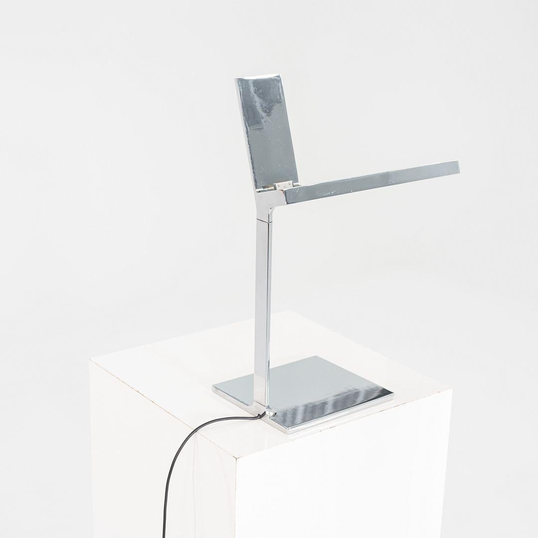 This is a D'E-light table lamp, originally designed by Philippe Starck for Flos. This particular example was produced in 2014. The design is comprised of polished aluminum and features a flat LED light source integrated into a sleek, cantilevered