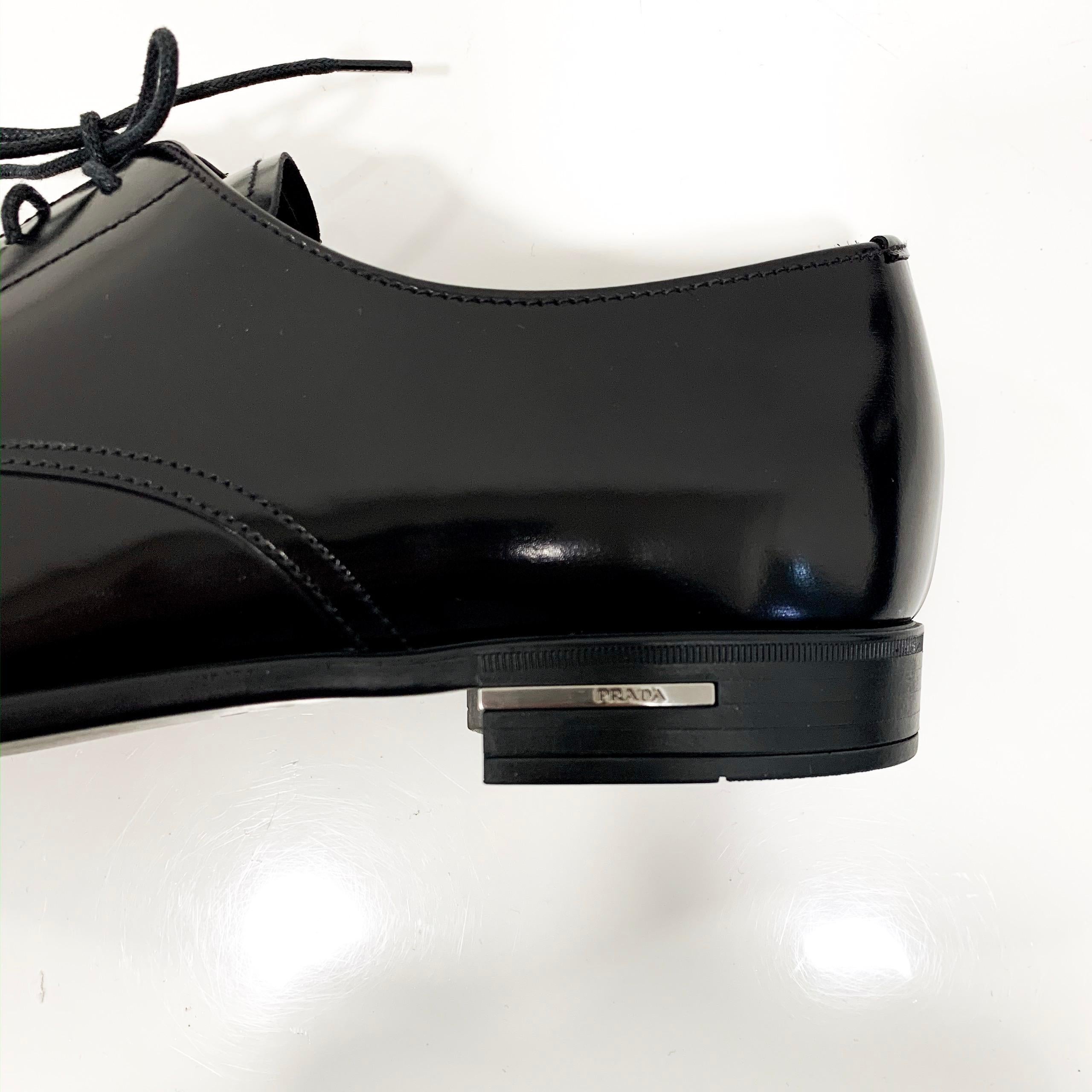 These Prada men’s Black derby patent leather shoes are made in Italy. The shoes feature leather laces, a rubber/leather sole, leather lining and also a Prada silver plaque logo on the heel. The leather is Prada famous spazzolato fume leather.