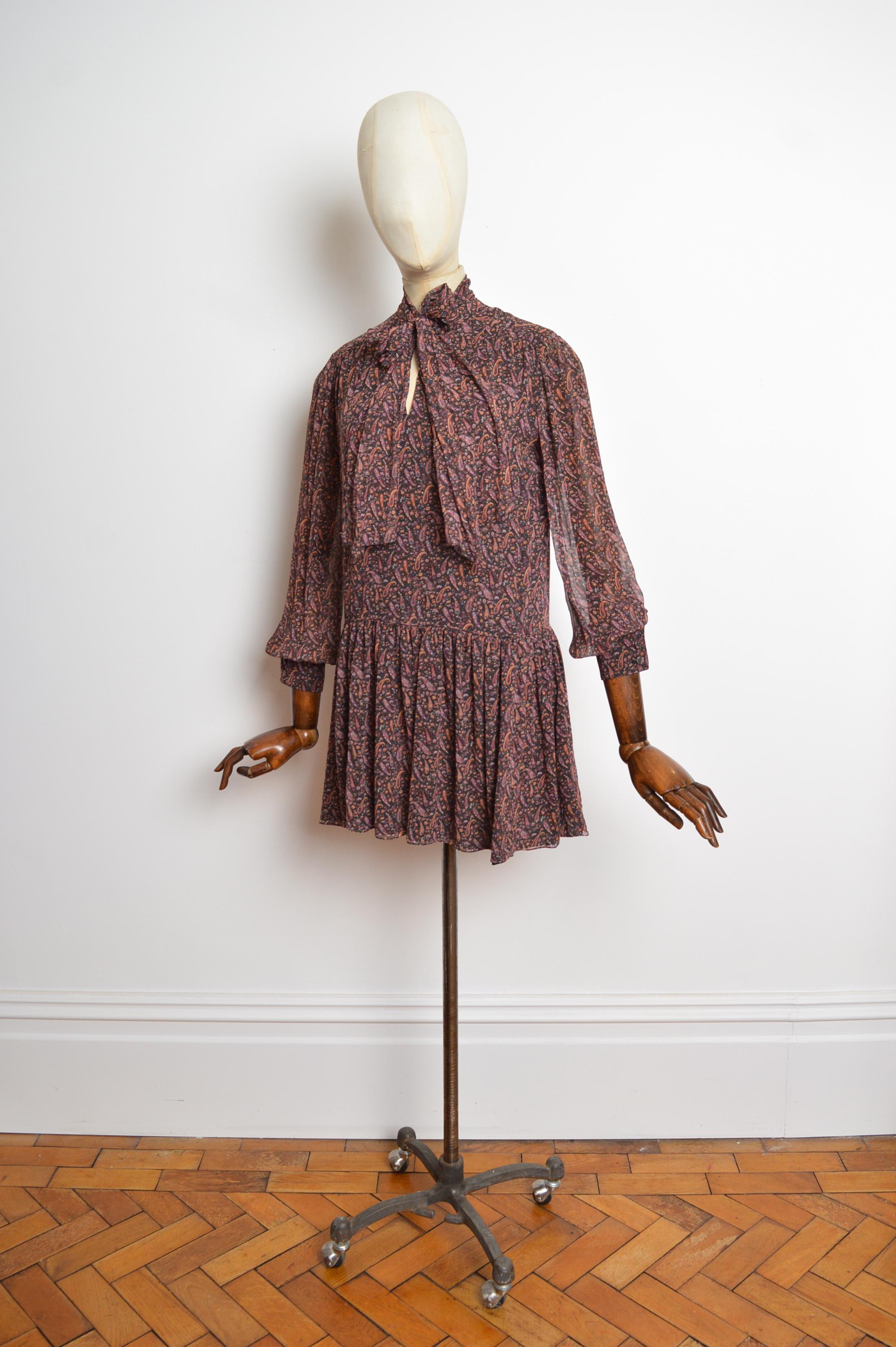 
2014 Saint Laurent by Hedi Slimane 1970's inspired Paisley, pussy bow collar mini dress featuring long sleeves with buttoned cuffs, fully lined interior and micro length. 
Size; recommended U.K. 6
Measurements are provided in inches (‘’)
Pit to