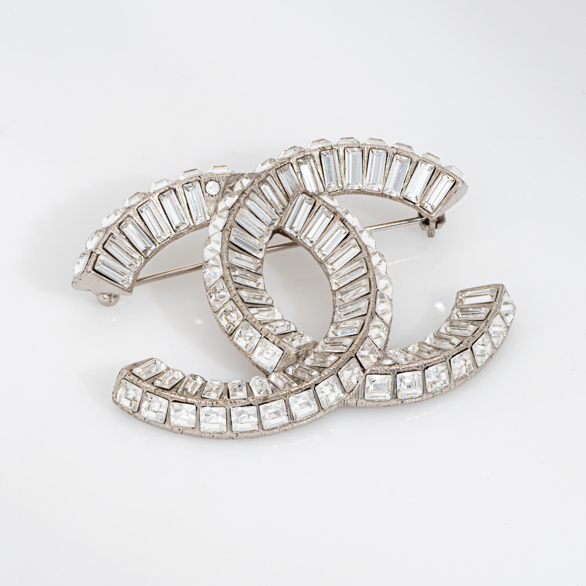Vue d'ensemble :

Authentique broche d'occasion Chanel Baguette crystal CC logo façonnée en ton argenté (circa 2015).

Des cristaux de taille carrée et baguette ornent la broche (en très bon état et sans fissure ni éclat).

La broche avec le logo