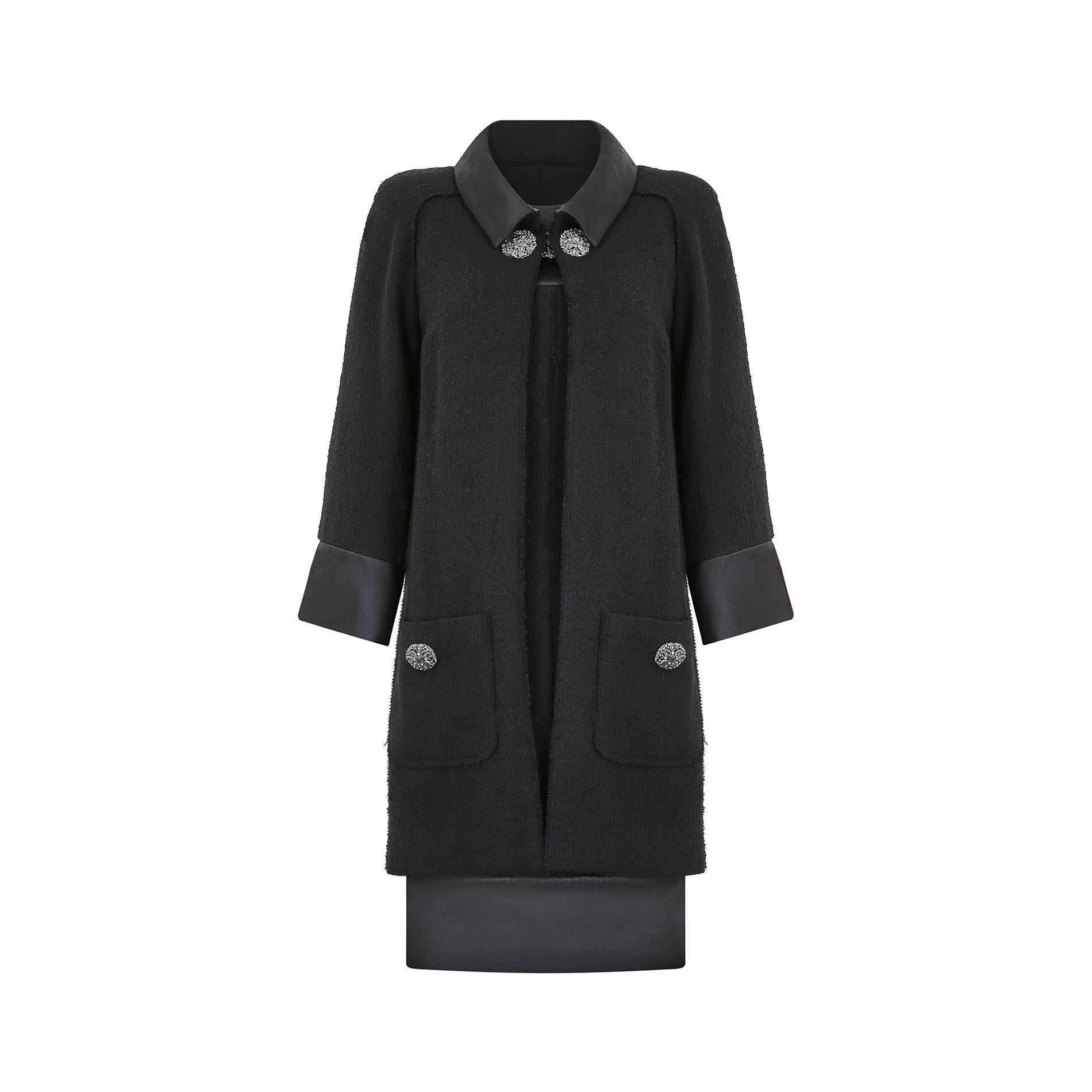 Ce fabuleux tailleur habillé noir automne-hiver 2015 Chanel by Karl Lagerfeld affiche une touche contemporaine tout en conservant les signatures classiques de la confection Chanel. La robe est coupée dans un style fourreau simple qui rappelle les