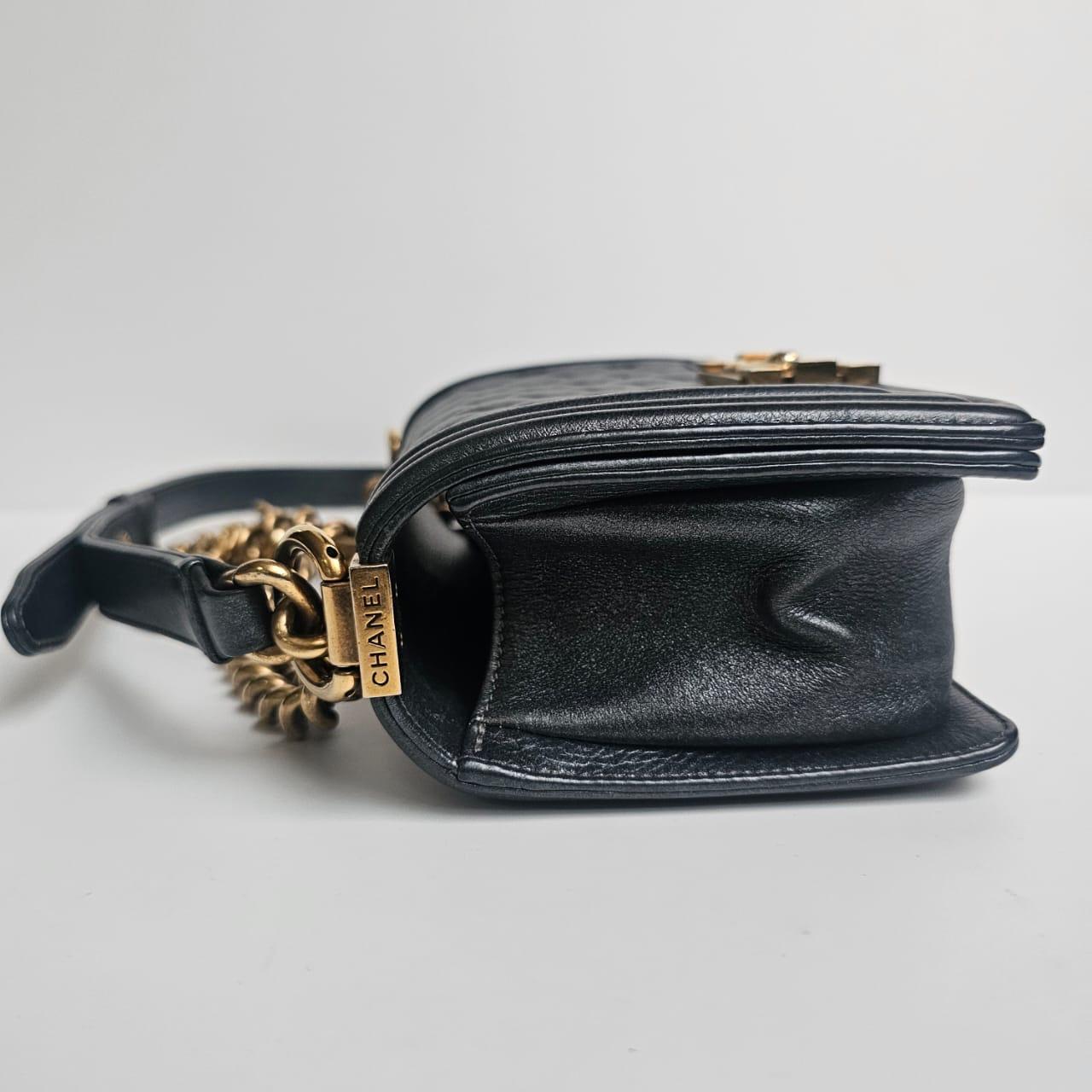 Sac classique de petite taille pour garçon, de couleur gris foncé métallisé avec des ferrures dorées rustiques. L'ensemble est encore en très bon état, avec un léger assouplissement du cuir. Quelques légères marques de frottement sur certaines