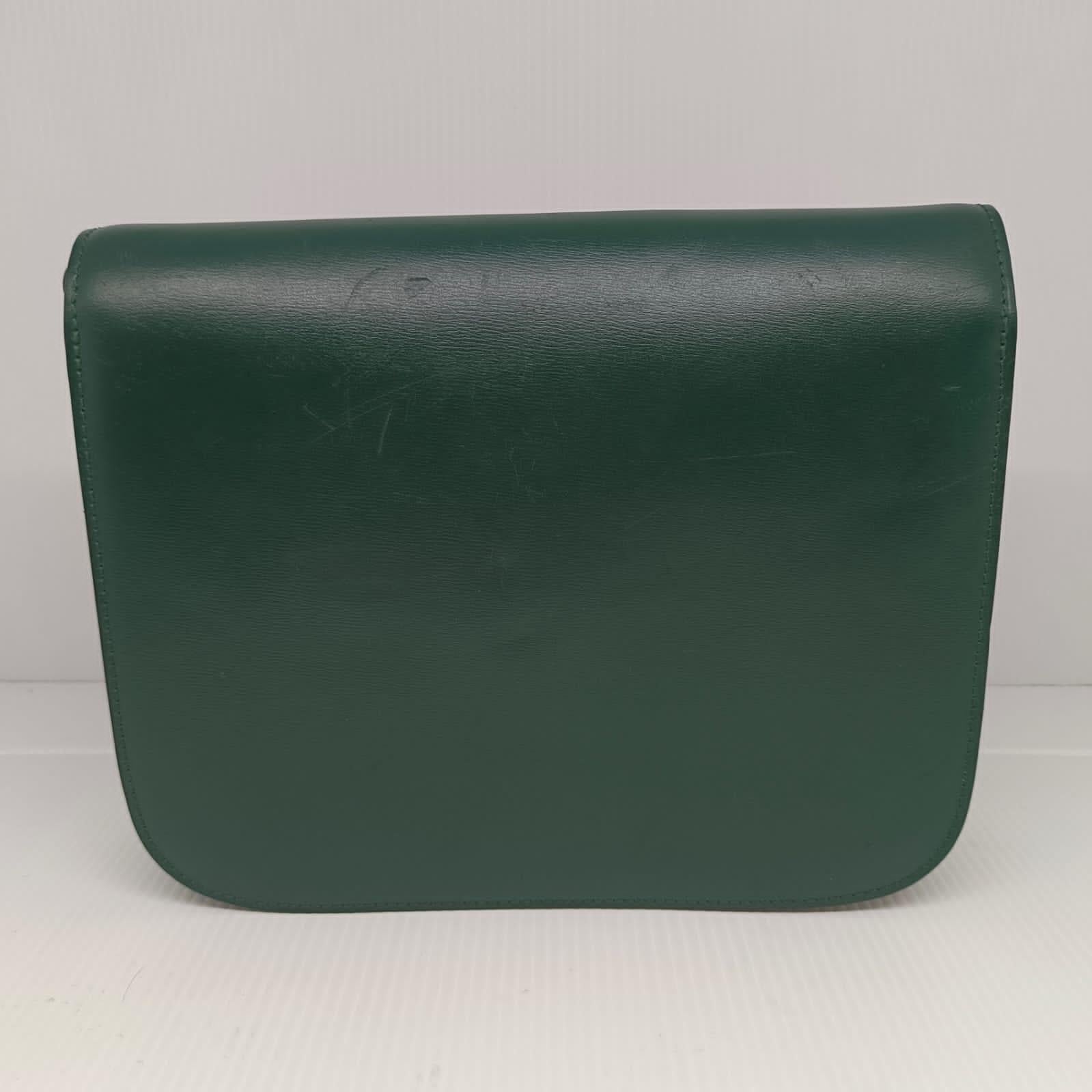 Celine medium box bag in emerald green with gold hardware. Visible dents and scratches throughout the leather surface. Very minor crack on the strap hole due to usage. Comes as it is. Adjustable strap.