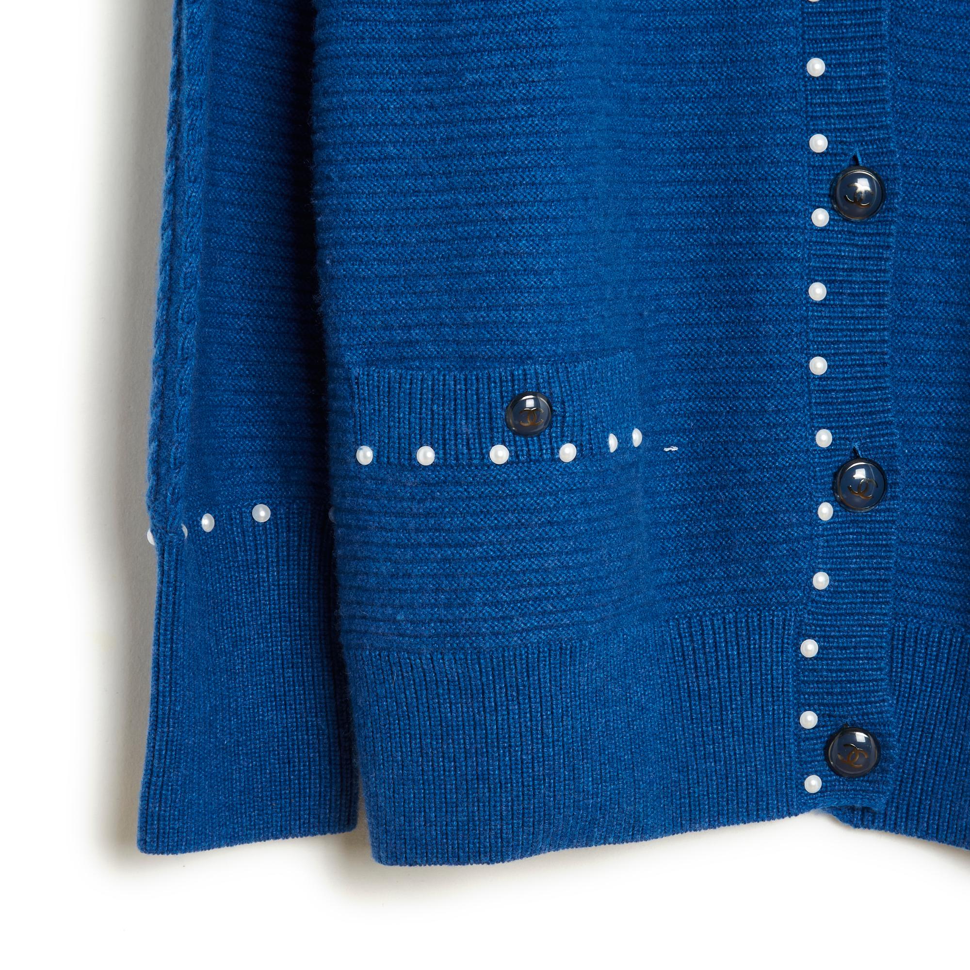 Chanel Strickjacke circa 2016 aus Baumwollstrick (53%) und Kaschmir mit königsblauen Zwirbeln, geschlossener V-Ausschnitt und Taschen, die mit geschwärzten silbernen Metallknöpfen geschlossen werden, rundum mit Halbperlen eingefasst, gerippte