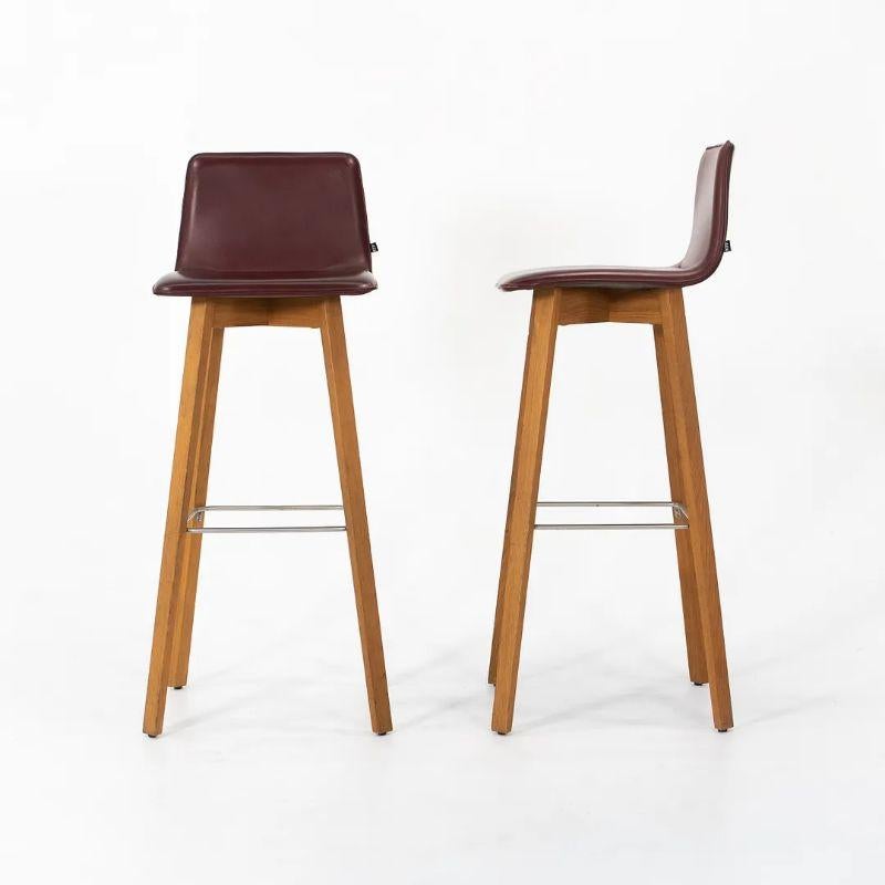 This is a Maverick Bar Stool, designed by Hoffmann Kahleyss for Karl Friedrich Forster (KFF Design). The piece was designed and manufactured in Germany. It features dark burgundy leather upholstery, and wood legs.

The listed price includes one
