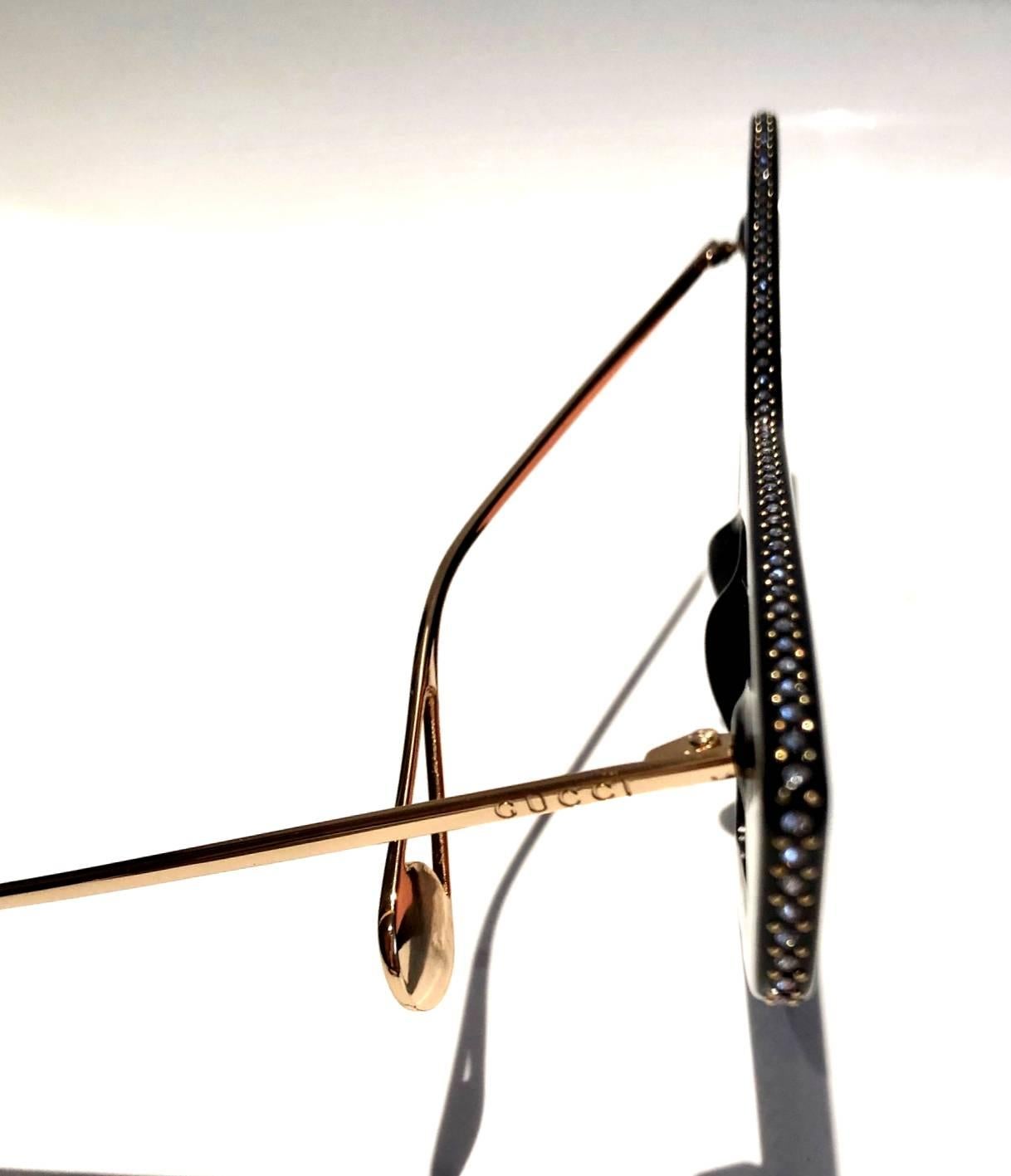 Gucci GG0430S 001 70 sunglasses feature an over exaggerated geometric cat eye frame, black frame, brown lenses, these premium havana acetate sunglasses are embellished with crystal Swarovski on the profile and feature stylish gold coated arms. The