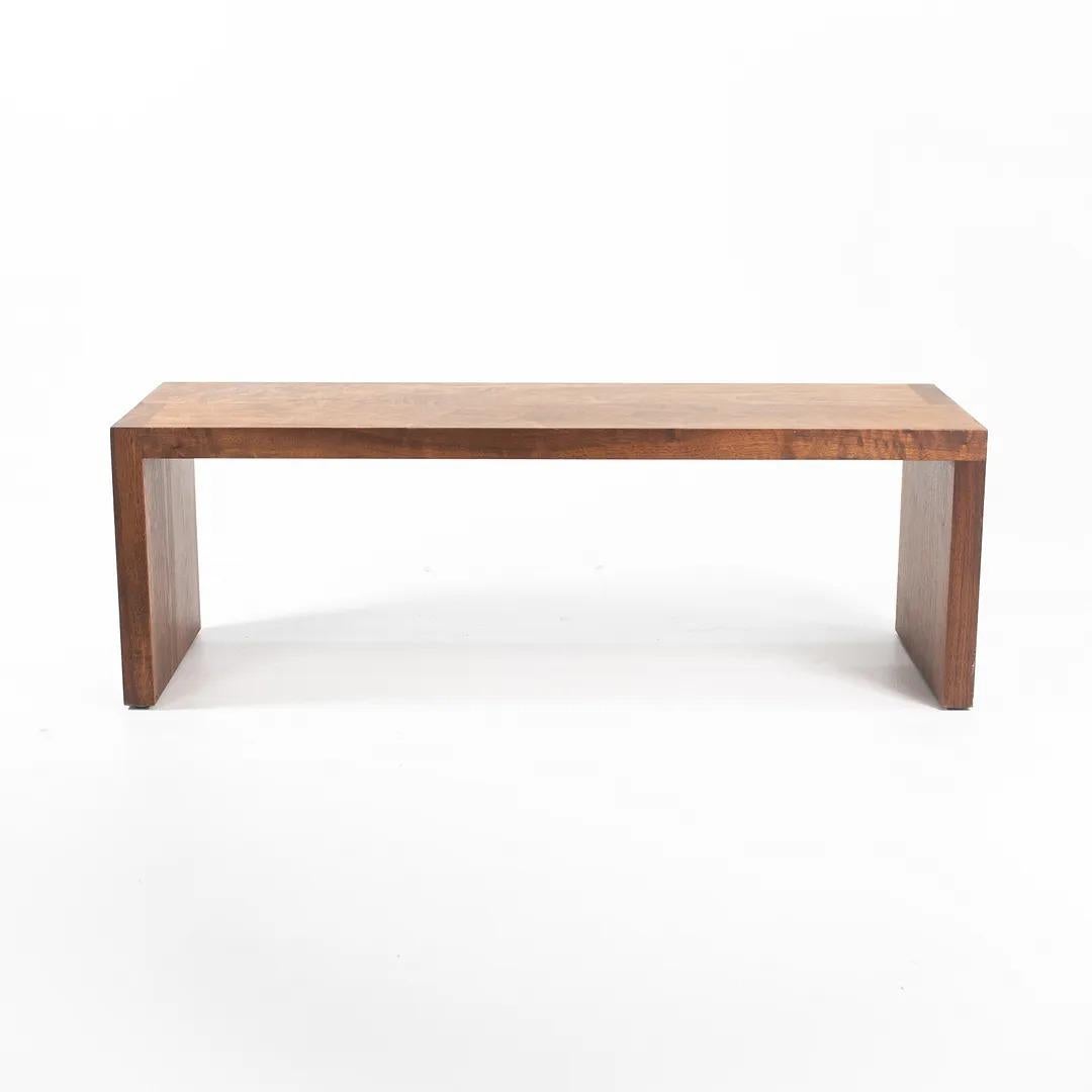 This is an “Axel” Bench, designed by Tyler Hayes for BBDW. The piece is composed of solid American Black Walnut slabs, having an applied oil finish. The design features straight-cut pieces of thick timber, each carefully selected for their grain