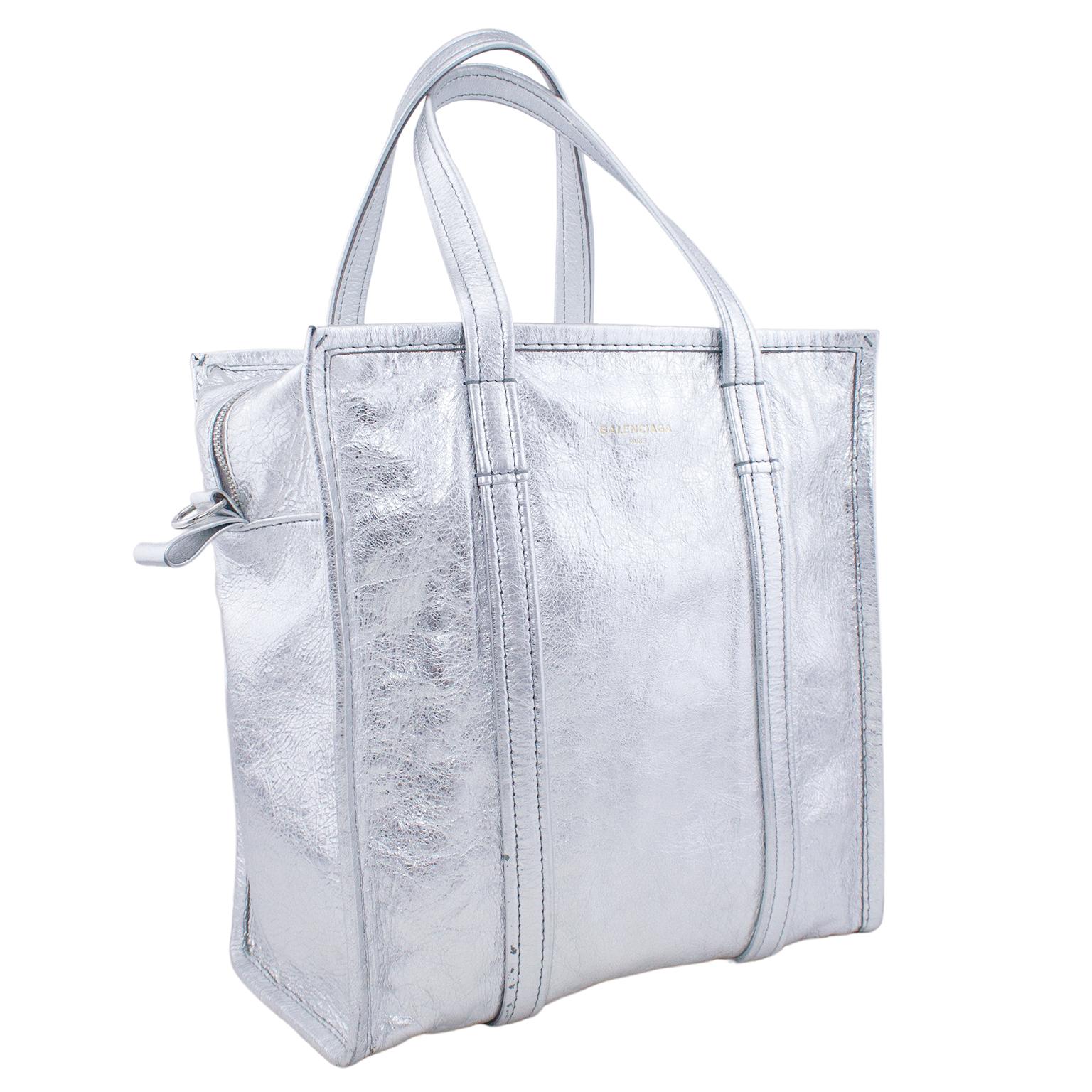 If you’ve been looking for the perfect statement bag to add to your collection, this silver Balenciaga Aaj Bazar Shopper Tote is for you. Made out of an aluminum-esque, 100% leather, the square-shaped tote is a minimal yet eye-catching statement