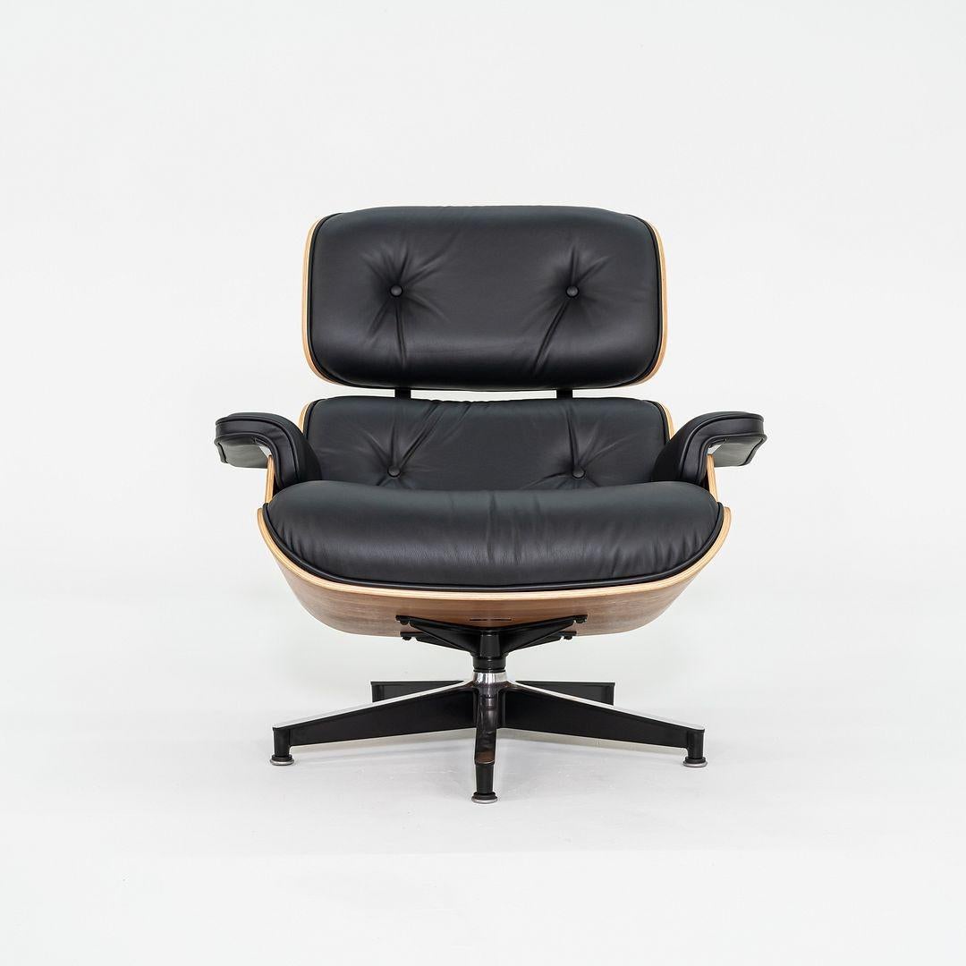 This is a Tall Eames Lounge Chair and Ottoman, models 670T and 671T, designed by Charles and Ray Eames for Herman Miller in 1956. This particular example dates to 2018. These pieces are comprised of walnut-veneered plywood shells and cushions