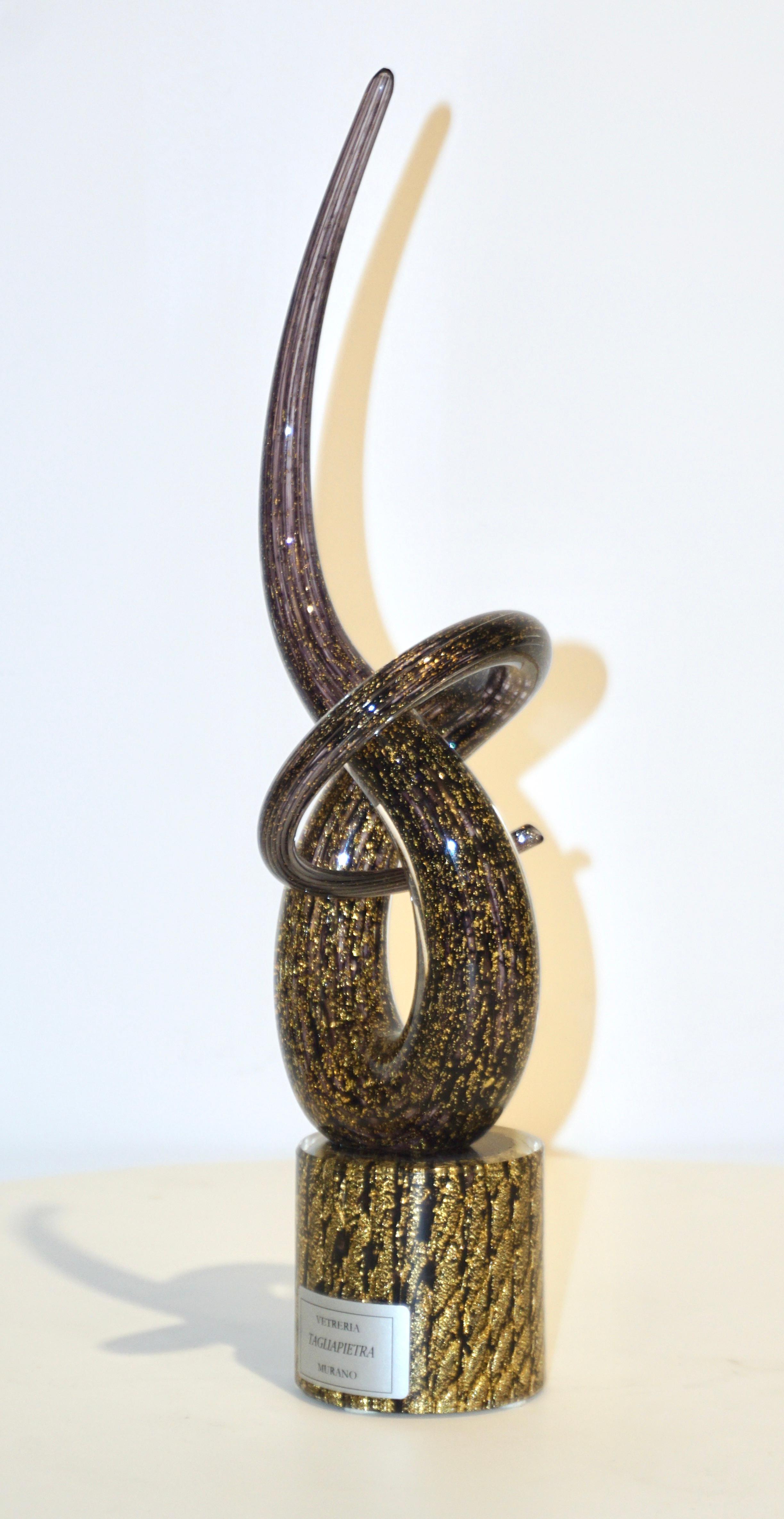 Sculpture abstraite contemporaine de boucles en nœud d'amour, au dessin sensuel tourbillonnant et spiralé, montée sur une base ronde, en verre de Murano soufflé améthyste foncé très spécial, largement travaillé à l'or pur dans le verre par Vetreria