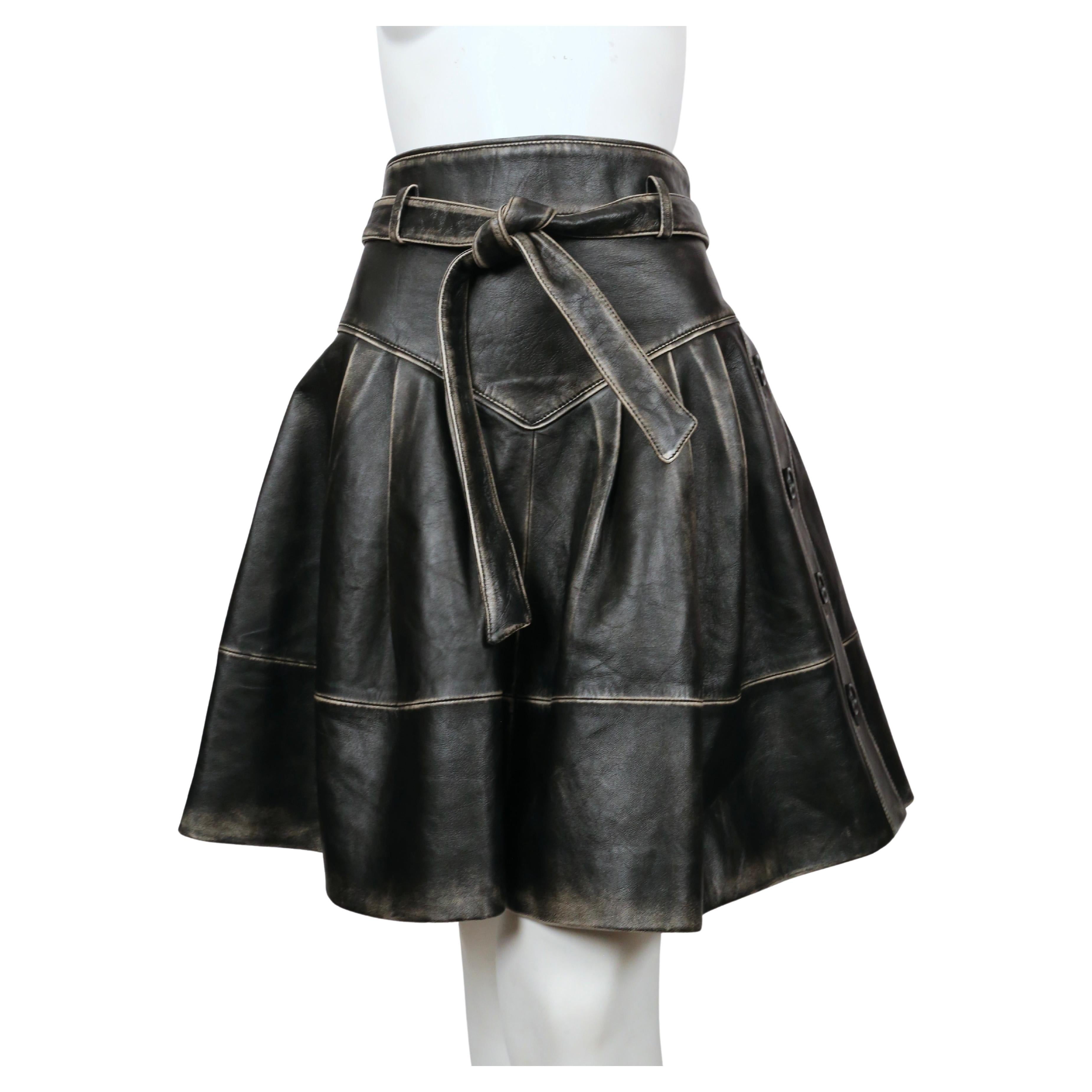 Distressed, black-brown leather skirt with belt and side button detail from Miu Miu dating to pre-fall 2018. Skirt is labeled an Italian size 42. Approximate measurements: waist 28