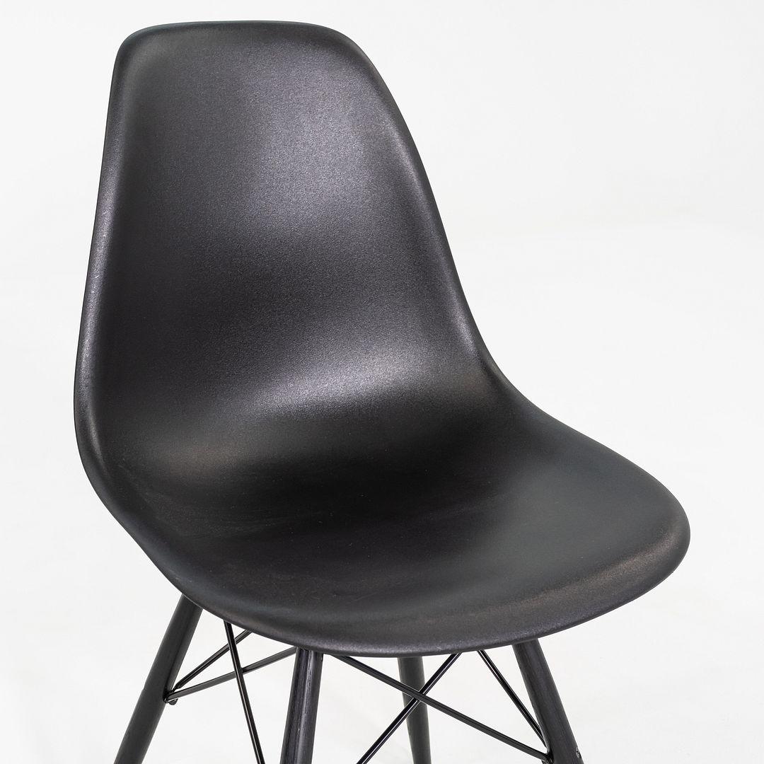 Il s'agit d'une chaise DSW, conçue à l'origine par Charles et Ray Eames pour Herman Miller en 1950. Cet exemple particulier a été produit aux États-Unis en 2018. La chaise est composée d'une coque en plastique moulé noir, d'une base en bois massif