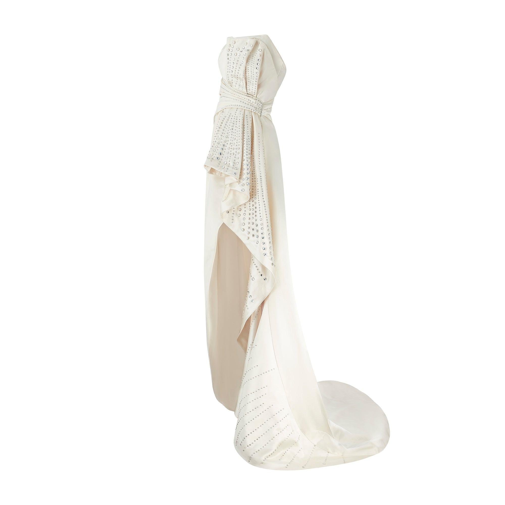 Alberta Ferretti designed this dress in 2019. Couture-crafted, it was made for actress Eva Longoria, who wore it to the Cannes Film Festival the same year. Generously designed from swathes of creamy white silk, it is tailored to an extreme