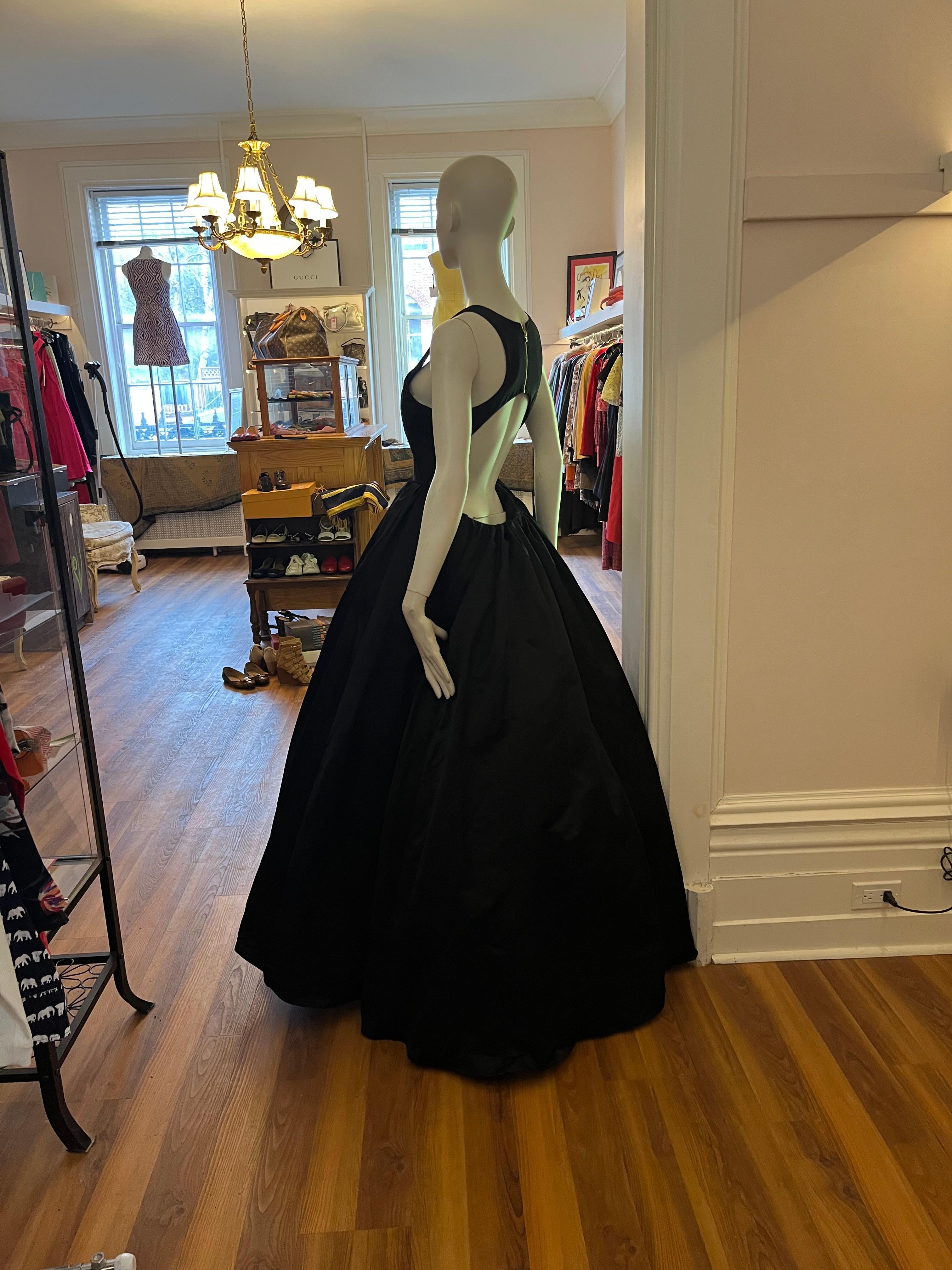 Be the belle of the ball! This is a fabulous black duchess satin scoop neck and open back gown. Nice wide zip detail at the back, and voluminous crinolines. The proportions are designed to feature you at your best.

This is the same model as the