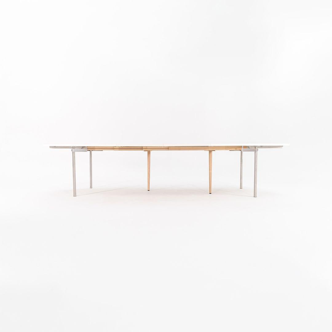 Se trata de una Mesa de Comedor Extensible CH336 fabricada con tablero laminado blanco y patas de acero cepillado. La mesa, diseñada por Hans Wegner y producida por Carl Hansen & Son en Dinamarca, data de hacia 2019 y está garantizada como
