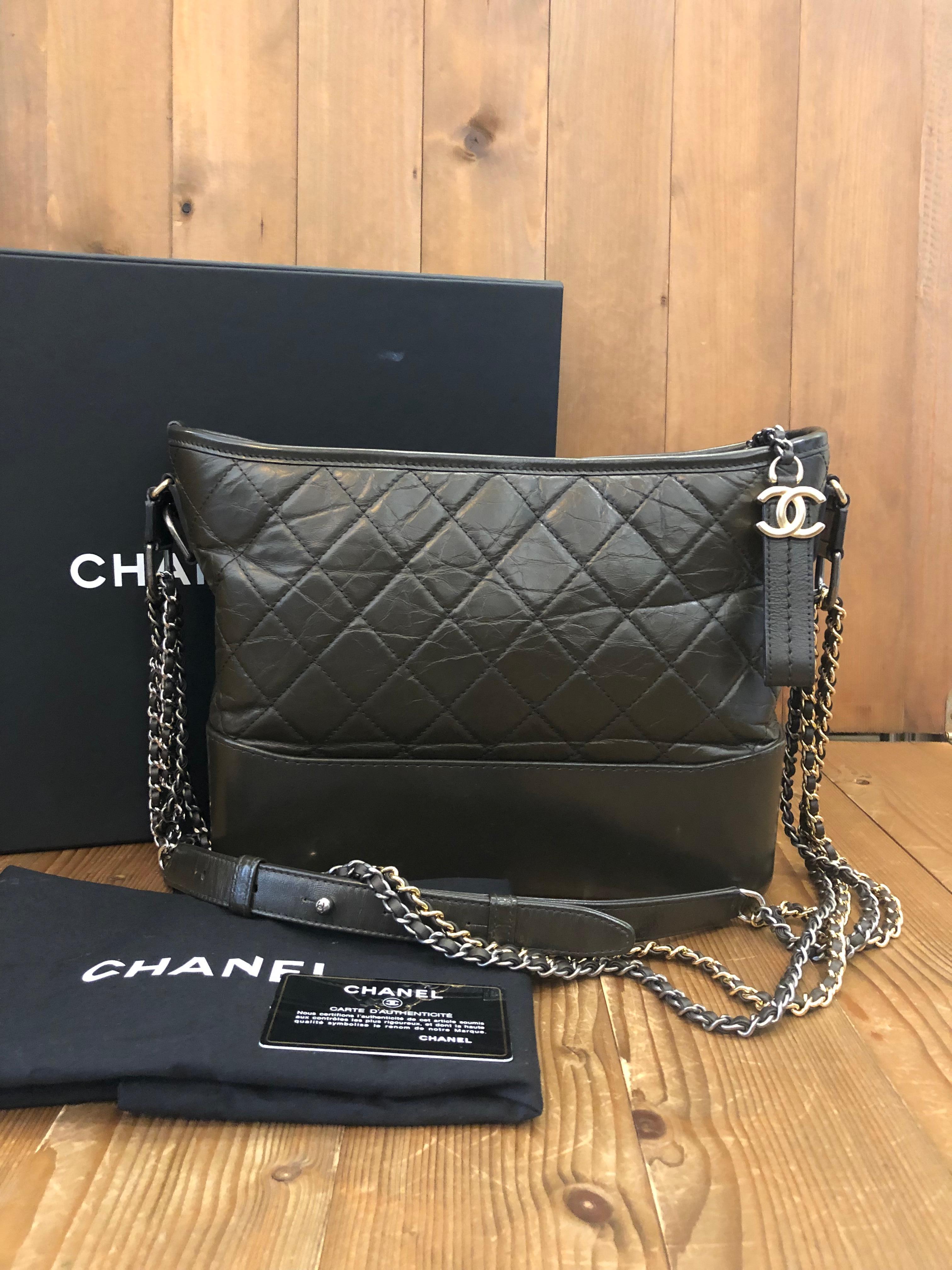 This 2019 CHANEL Gabrielle hobo bag is crafted of distressed calfskin leather in dark green featuring one interior zip pocket and two interior open pockets. Medium in size. Duel toned shoulder chains interlaced with the same leather. Made in Italy.