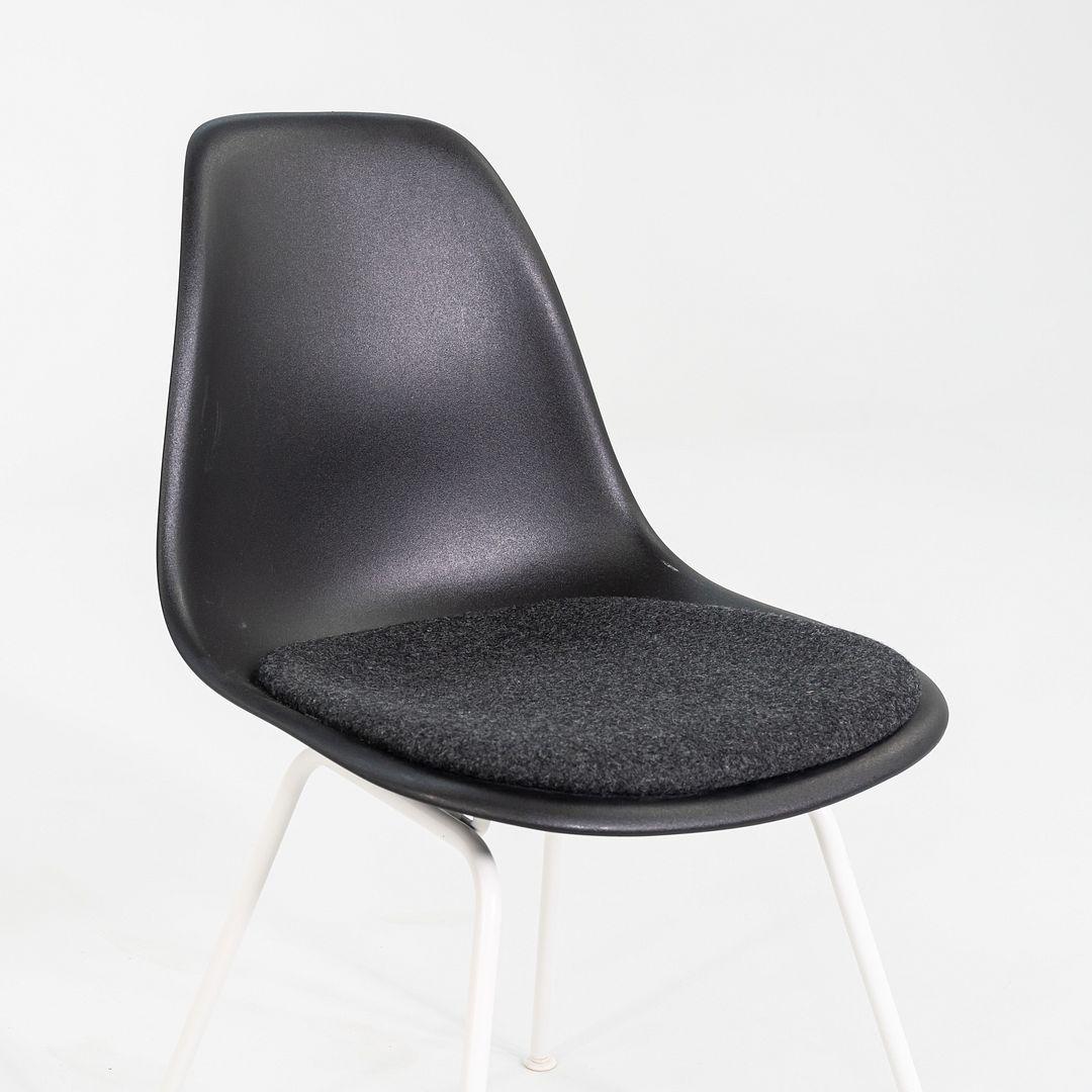 This is a pair of DSX side chairs, originally designed by Ray and Charles Eames in the 1950s. These particular examples were produced by Herman Miller in the USA C. 2019. The chairs are comprised of a black plastic shell with a fabric seat atop a