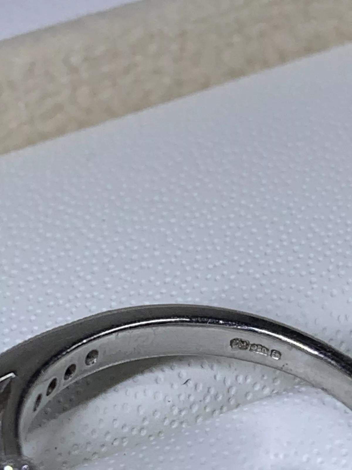 Cette magnifique bague de fiançailles est fabriquée de manière experte en platine 950 et met en valeur un diamant rond de 2,01ct à couper le souffle, certifié par le GIA. Le diamant est serti dans un halo et complété par un diamant secondaire, ce