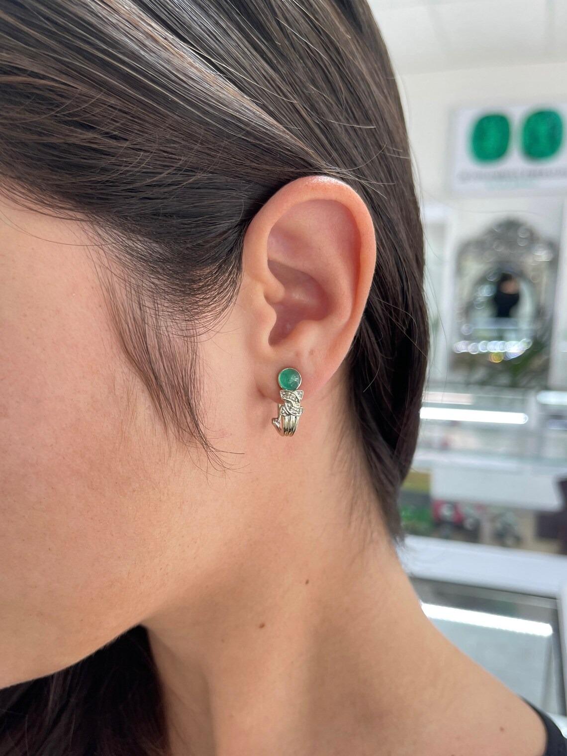 A gorgeous pair of cabochon and diamond accent earrings. This dainty pair showcases two stunning, spring bluish-green emerald cabochons from the origin of Colombia. The emerald cabs are carefully bezel set, with diamond accents at the bottom.