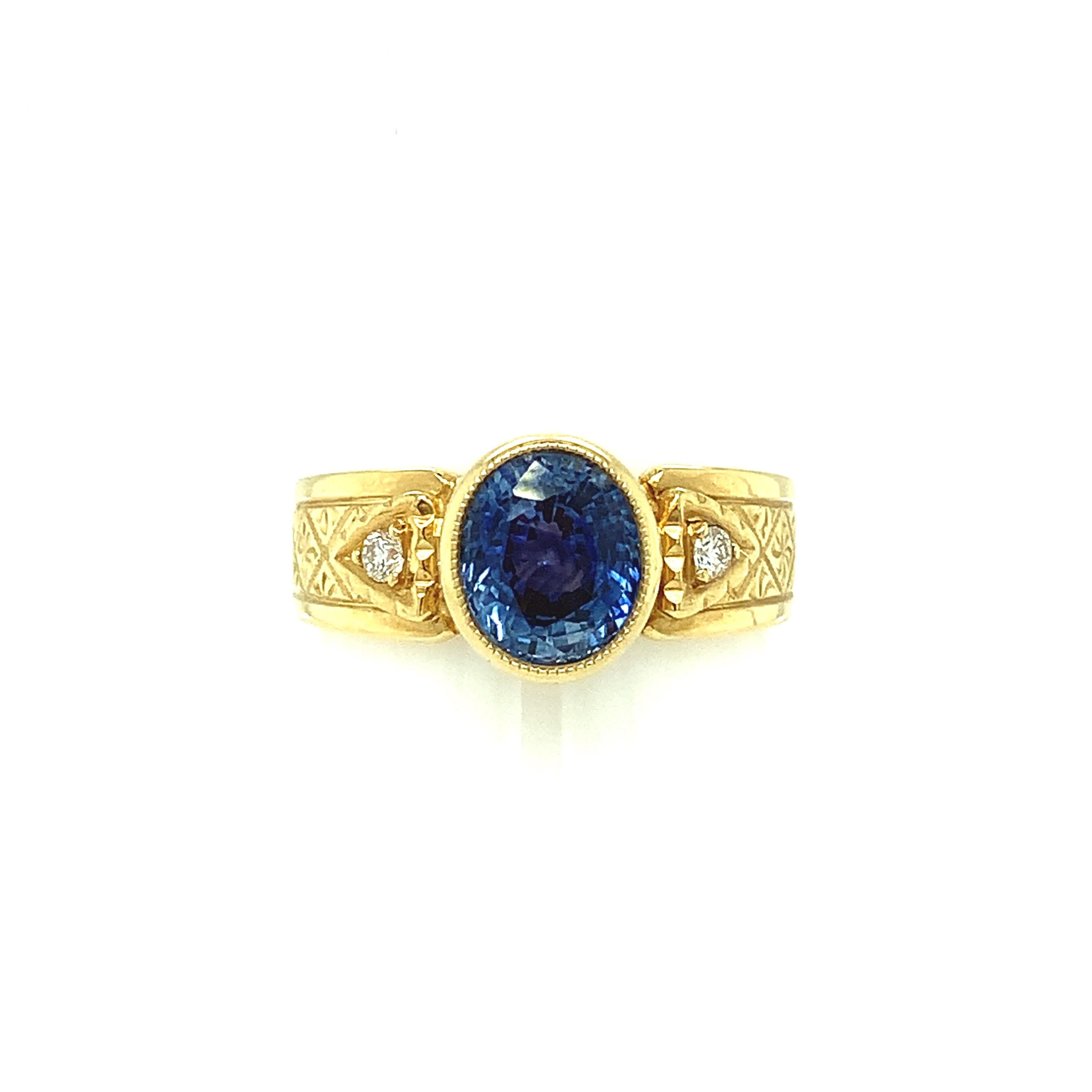 A bright, 2.02 carat oval blue sapphire is featured in this handmade 18k yellow gold ring. The sapphire is a beautiful medium blue color and well-cut, giving it exceptional brilliance and life. The band is accented with two sparkling white diamonds