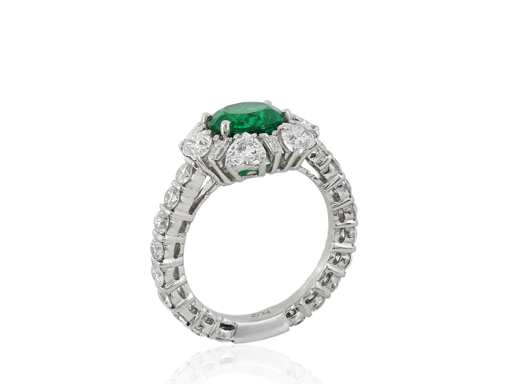 Platinum estate cluster ring consisting of 1 round brilliant cut Colombian emerald weighing 2.02 carats set with 2.86 carats total weight of round brilliant cut, heart shape and baguette diamonds.