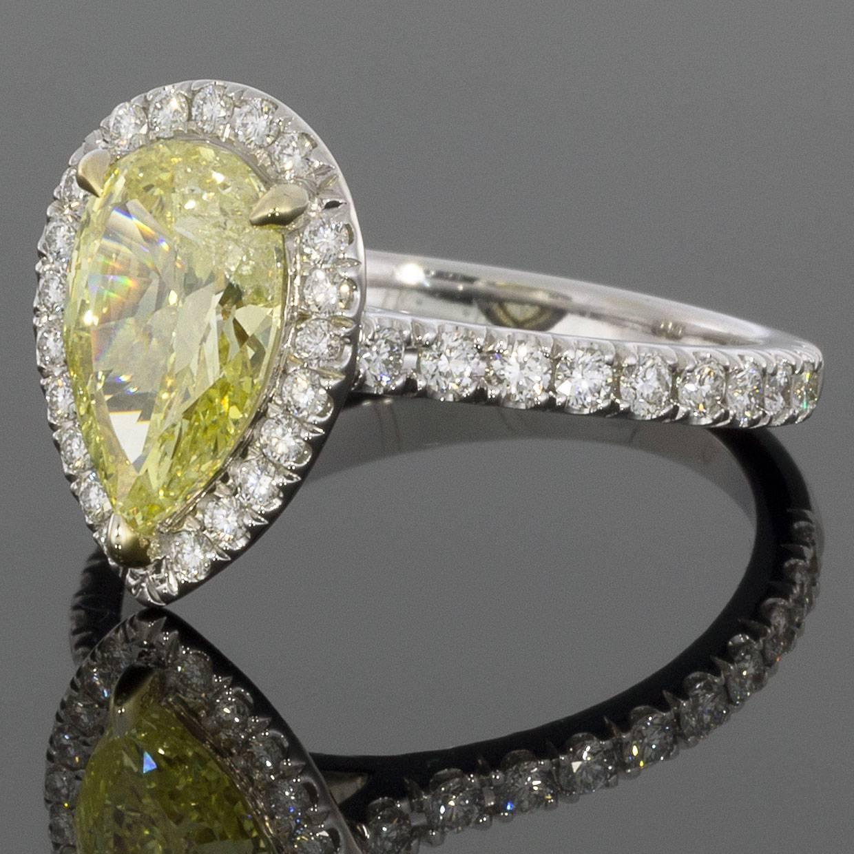 This gorgeous halo engagement ring features a stunning 1.56 carat fancy intense yellow, pear center diamond that is prong set in a yellow gold head on a custom made ring. This center diamond grades as Fancy Intense Yellow in color and is very well