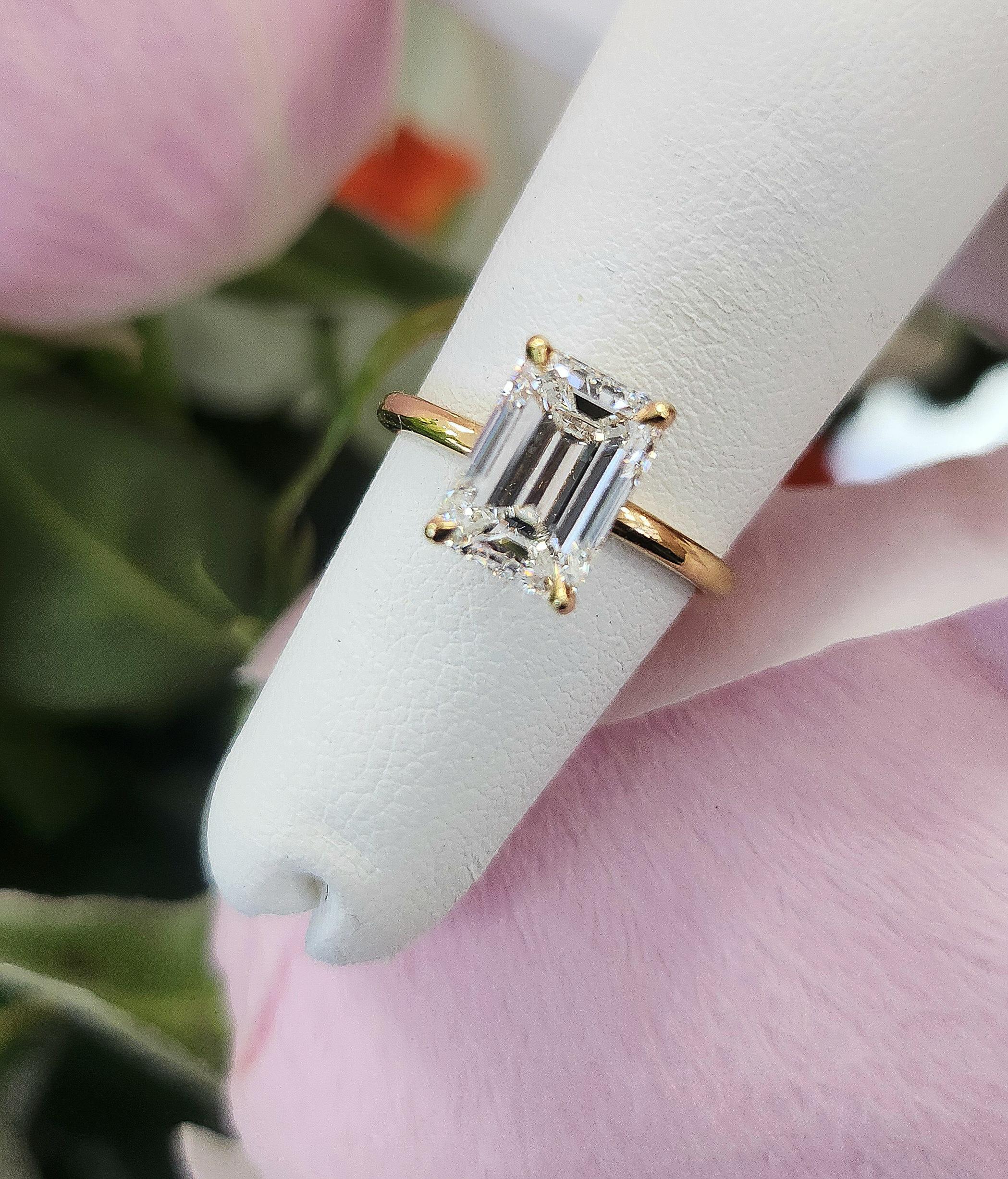 Cette bague de fiançailles exquise met en valeur un diamant taille émeraude de 2,02 carats, magistralement serti dans de l'or jaune 18 carats. La pierre centrale, de couleur G et de pureté VVS2 selon le Gemological Institute of America (rapport GIA