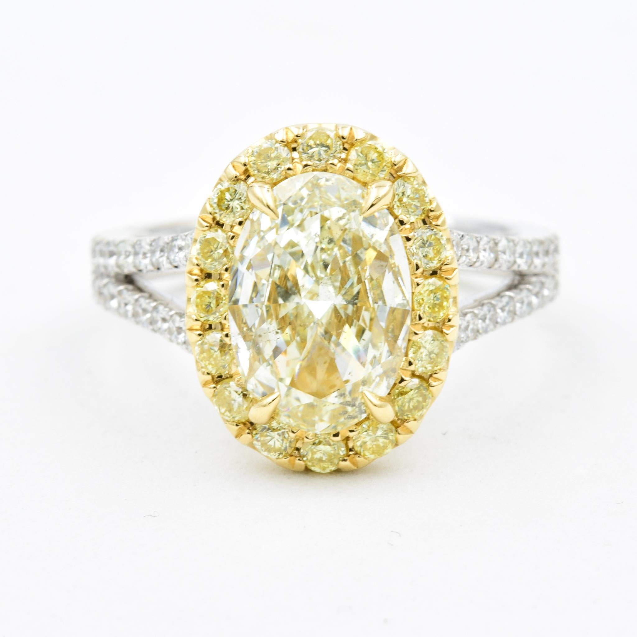 This beautiful diamond ring features a 2.02 carat Fancy Light Yellow diamond in an oval cut.  The diamond is accented by 0.46 carats of yellow diamonds set in 18k yellow gold.  The remainder of the mounting with the split shank style in 18k white