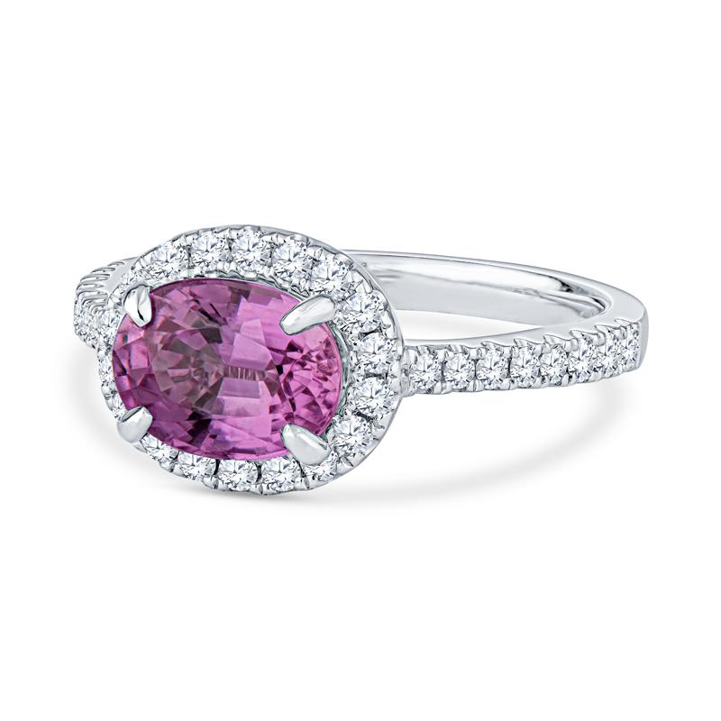This unique ring features a 2.02 carat oval pink sapphire, heat only, set east-west style accented by 0.38 carat total weight in round brilliant cut diamonds set in 14 karat white gold. This ring is a size 6 but can be resized upon request.