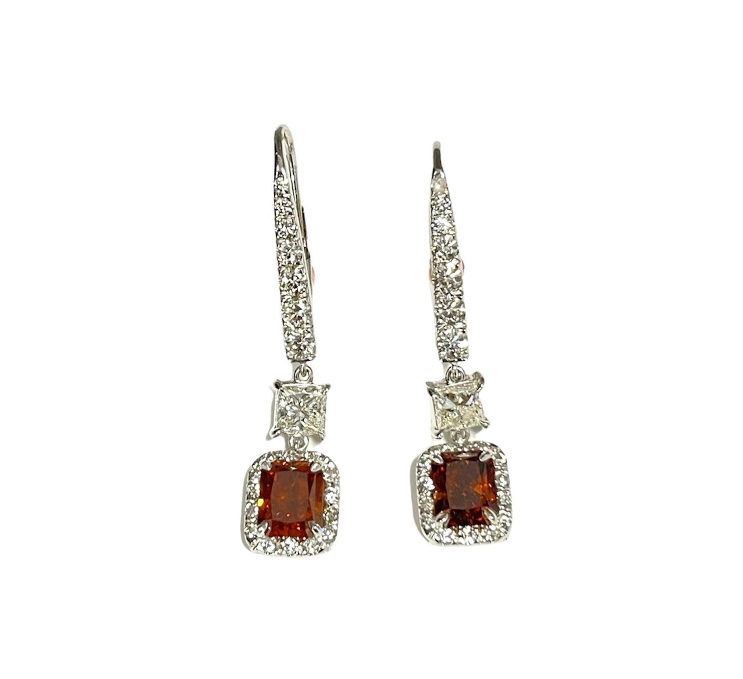 These stunning natural fancy deep orange-brown diamond earrings feature 2 natural GIA diamonds weighing 2.02 ct and 50 diamonds weighing 1.21 ct set in 18k white gold.
