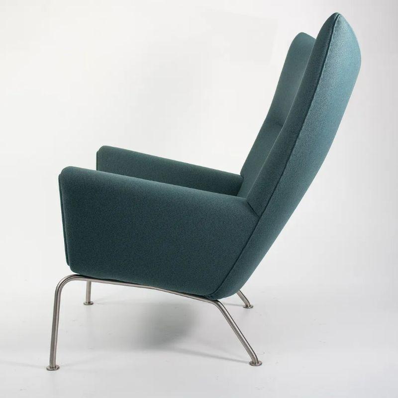 Nous proposons à la vente une chaise longue à oreilles CH445, composée d'une structure en acier inoxydable et d'un tissu vert foncé. La chaise a été conçue par Hans Wegner et produite par Carl Hansen & Son au Danemark. La chaise date d'environ 2020
