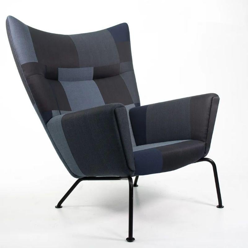 Listed for sale is a CH445 Wing Lounge Chair, made with a black powder coated stainless steel frame and grey/black/navy color blocked fabric. The chair was designed by Hans Wegner and produced by Carl Hansen & Son in Denmark. The chair dates to