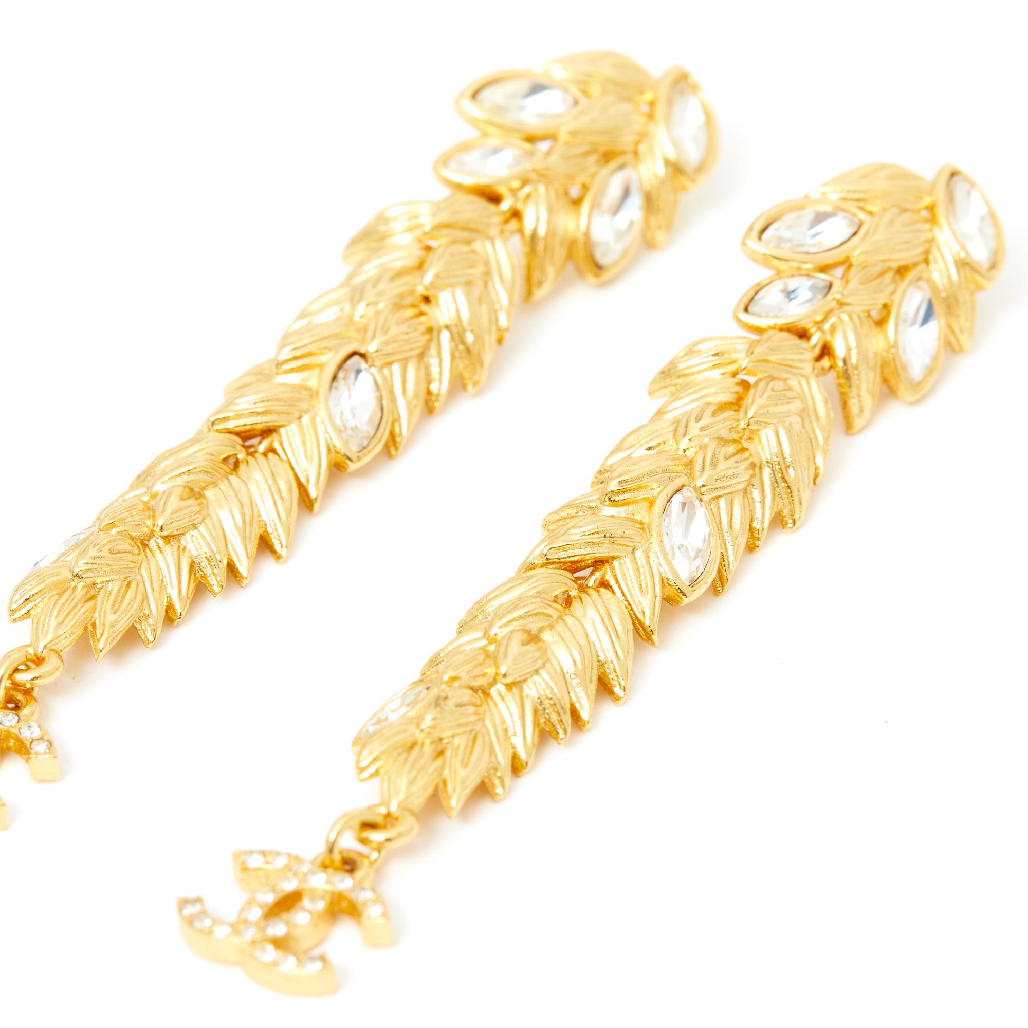 Chanel earrings, SS or Resort 2020 collection, gold metal studs with a foliage or ear of wheat motif inlaid with white shuttle rhinestones, small CC encrusted with rhinestones at the bottom of the buckle. Total length 7.4 cm x width 1.35 cm. The