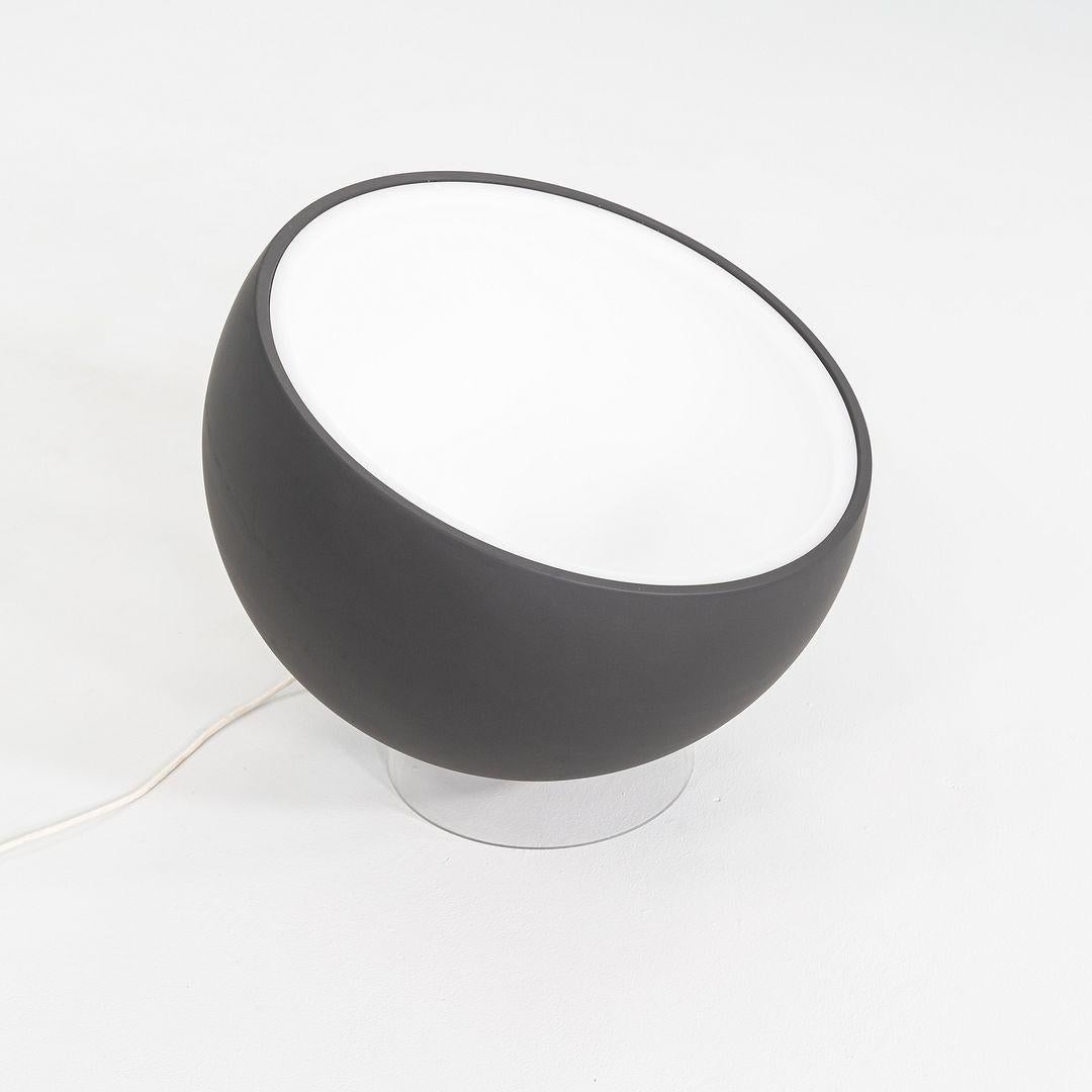 This is a Biluna Floor Lamp, originally designed by Luc Ramael for Prandina in 2008. This particular example was produced in Italy in 2020. The design is characterized by its large, hemispherical diffuser in grey acrylic, which rests on a white base